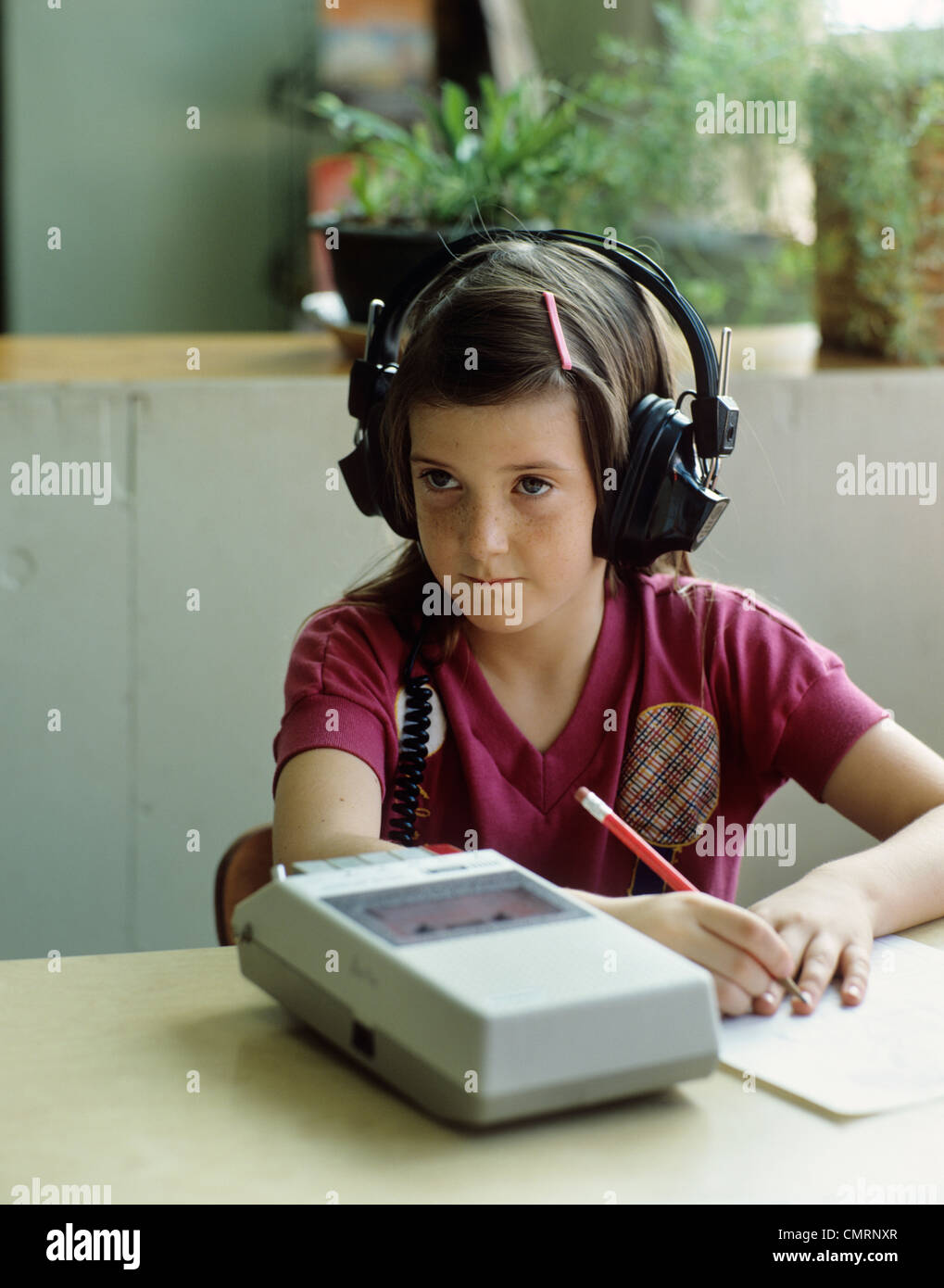 1980s LITTLE GIRL DOING HOMEWORK LISTENING TO  AUDIO CASSETTE TAPE Stock Photo