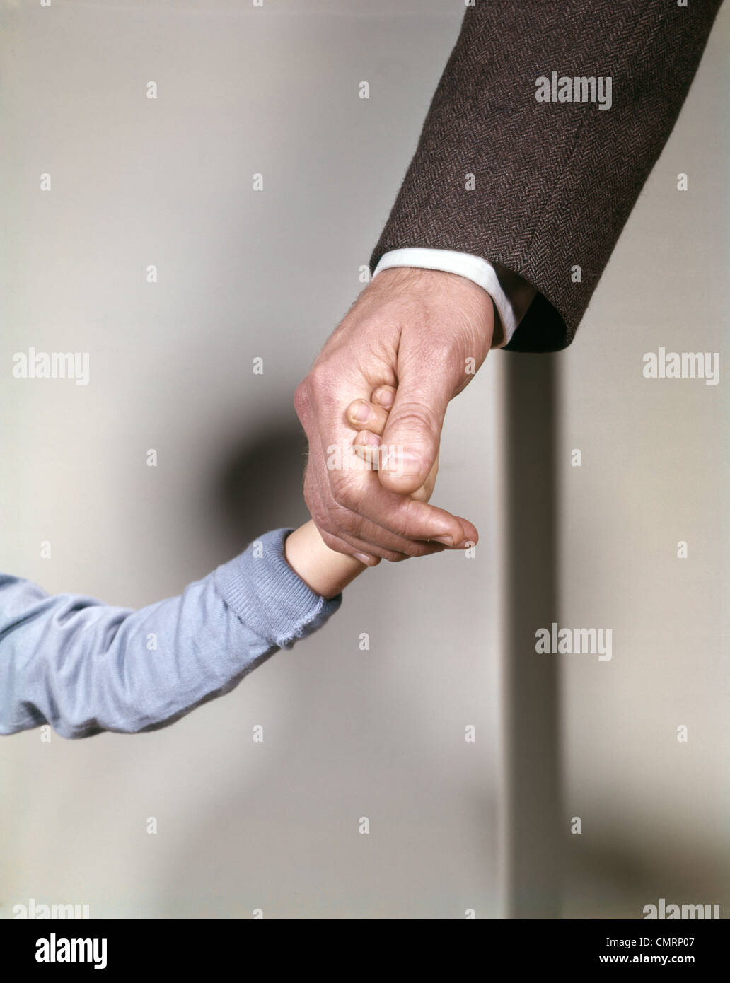 1960s ADULT MAN HAND HOLDING THAT OF SMALL CHILD TODDLER FATHER YOUNG OLD SAFETY PROTECTION GUIDANCE RETRO Stock Photo