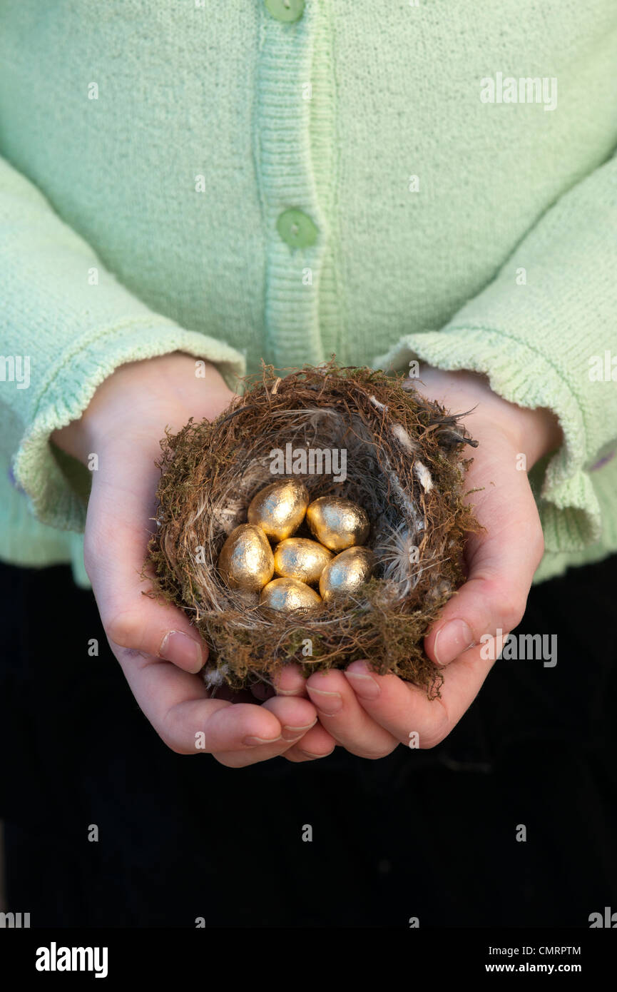 Girl holding golden eggs in a bird nest Stock Photo