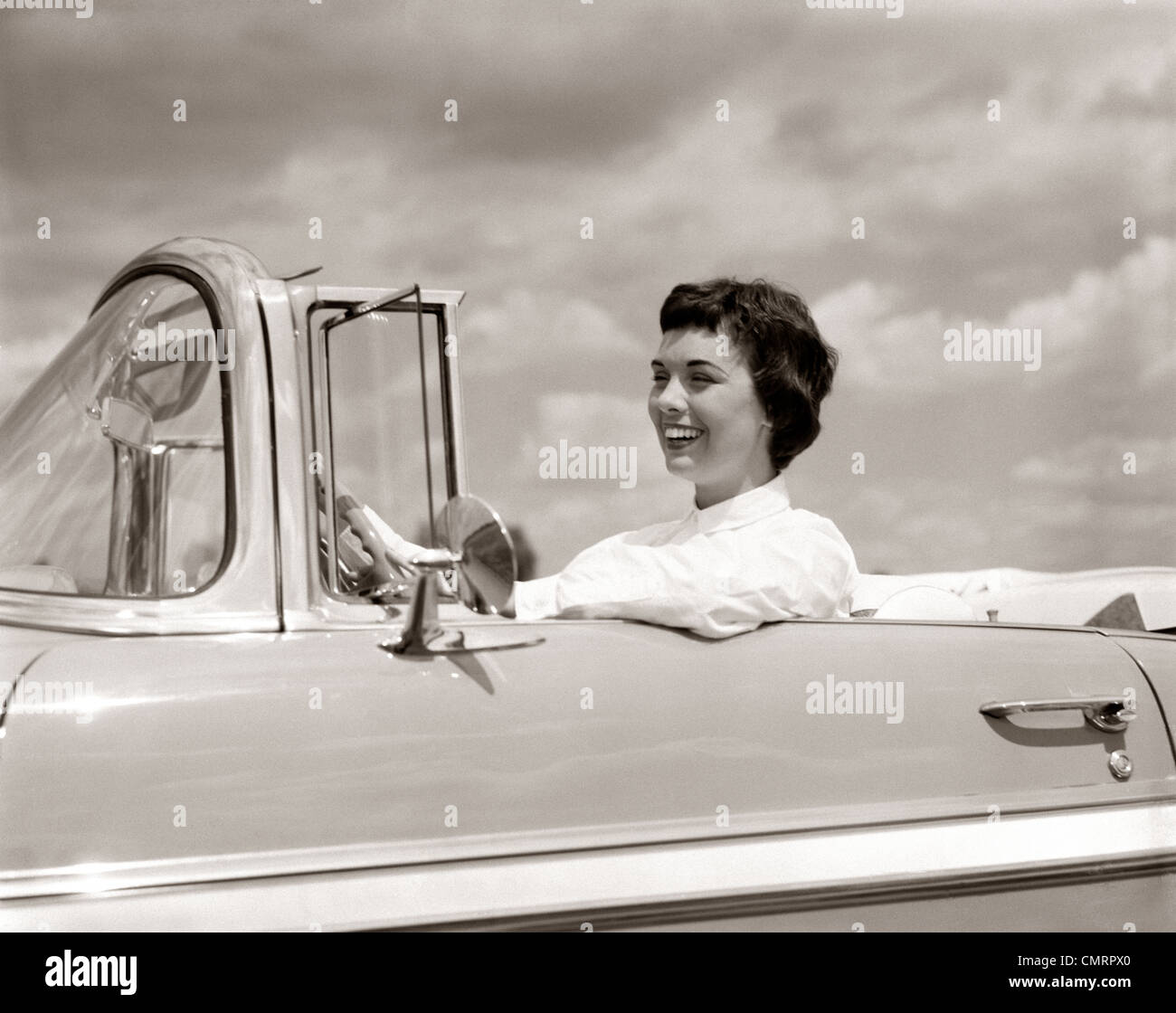 1950s SMILING WOMAN DRIVING CHEVROLET CONVERTIBLE AUTOMOBILE Stock Photo