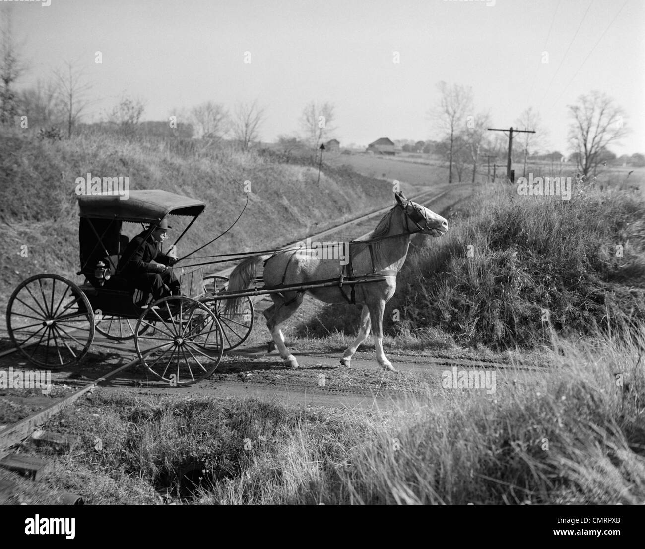 1890s 1900s RURAL COUNTRY DOCTOR DRIVING HORSE & CARRIAGE ACROSS RAILROAD TRACKS Stock Photo