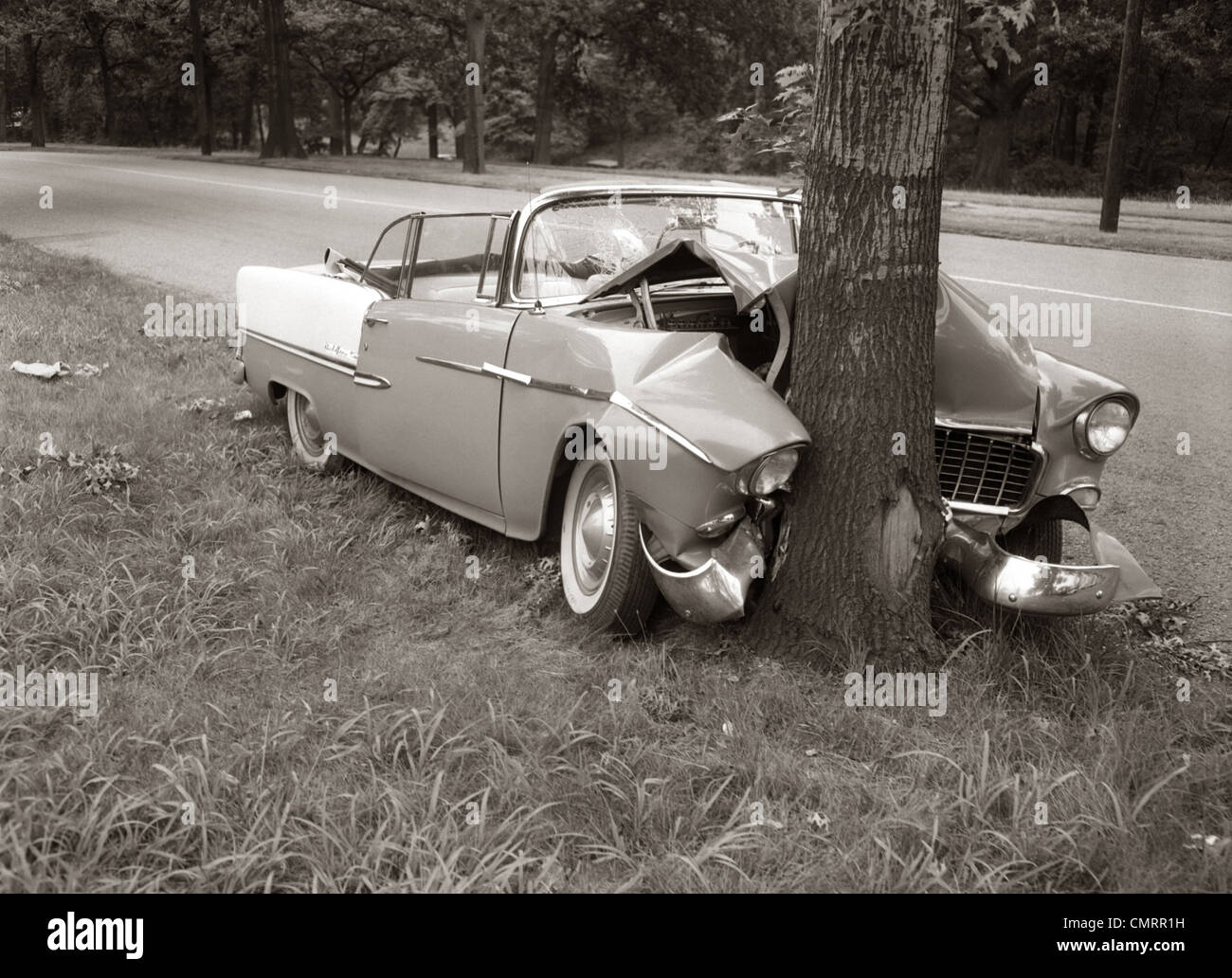 1950s CONVERTIBLE CRASHED HEAD-ON INTO A TREE OUTDOOR Stock Photo