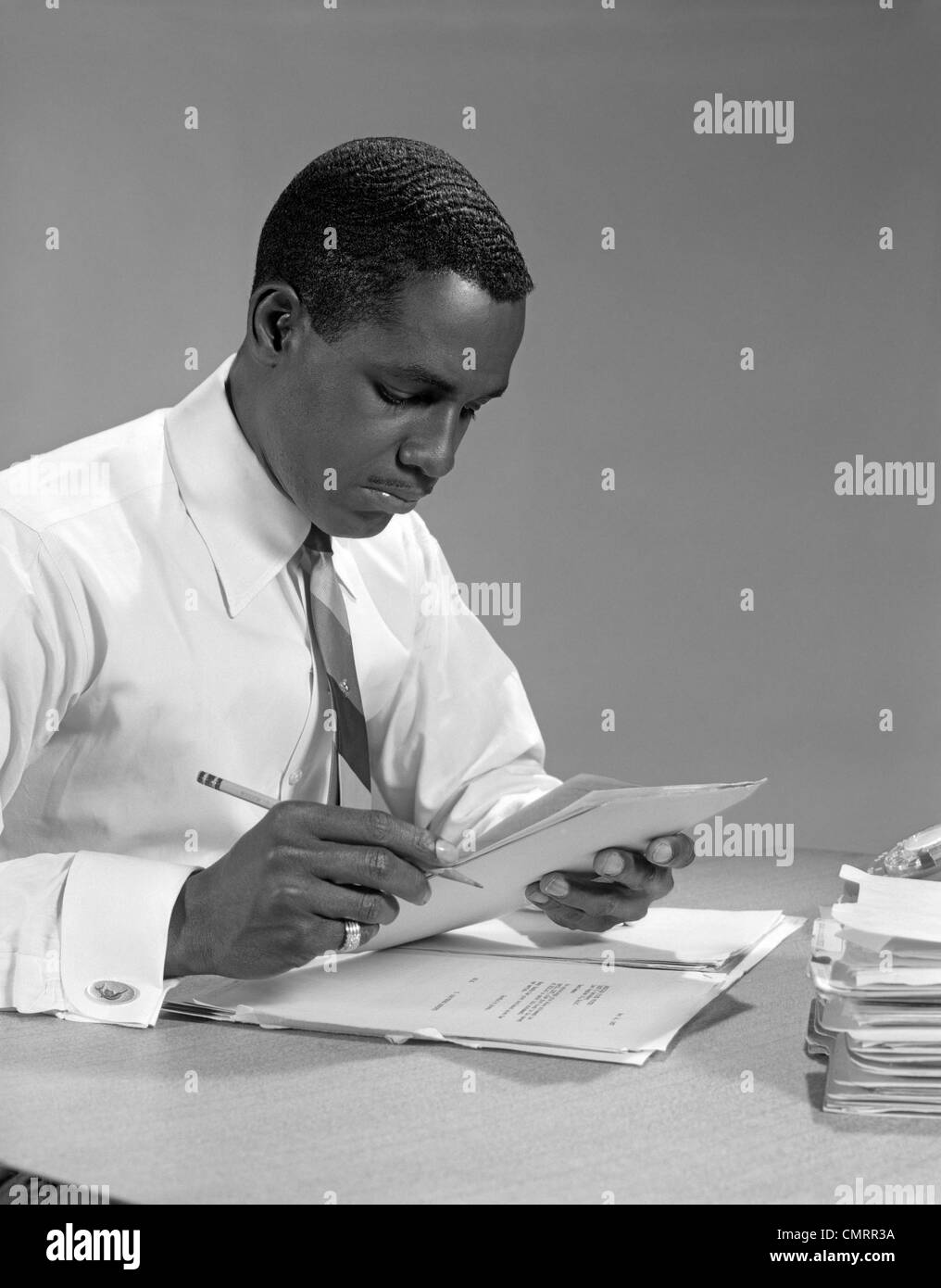 1960s AFRICAN AMERICAN MAN BUSINESSMAN WORKING DESK FILES PAPERS Stock Photo