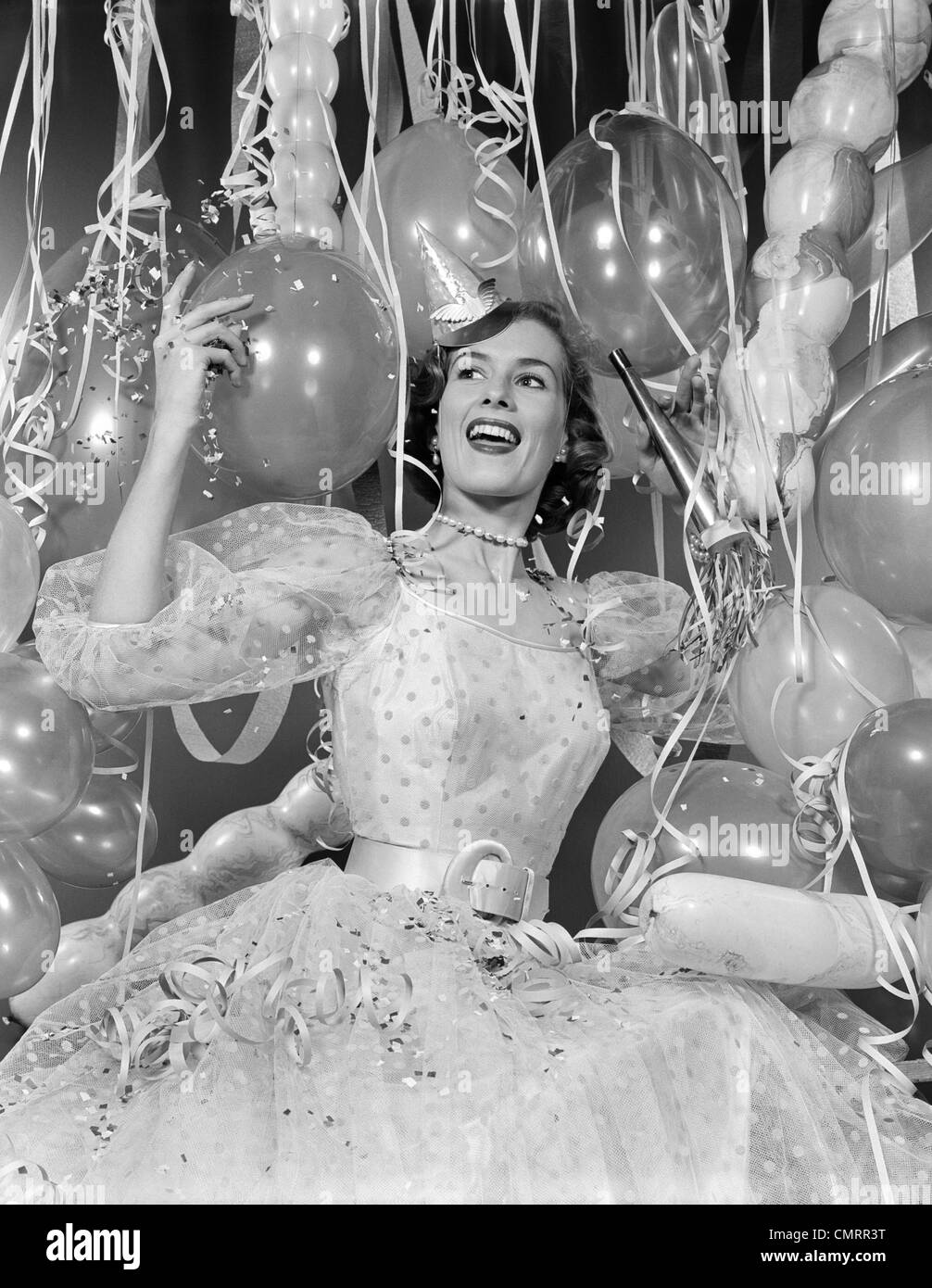 1950s WOMAN IN PARTY DRESS SURROUNDED BY STREAMERS & BALLOONS Stock Photo