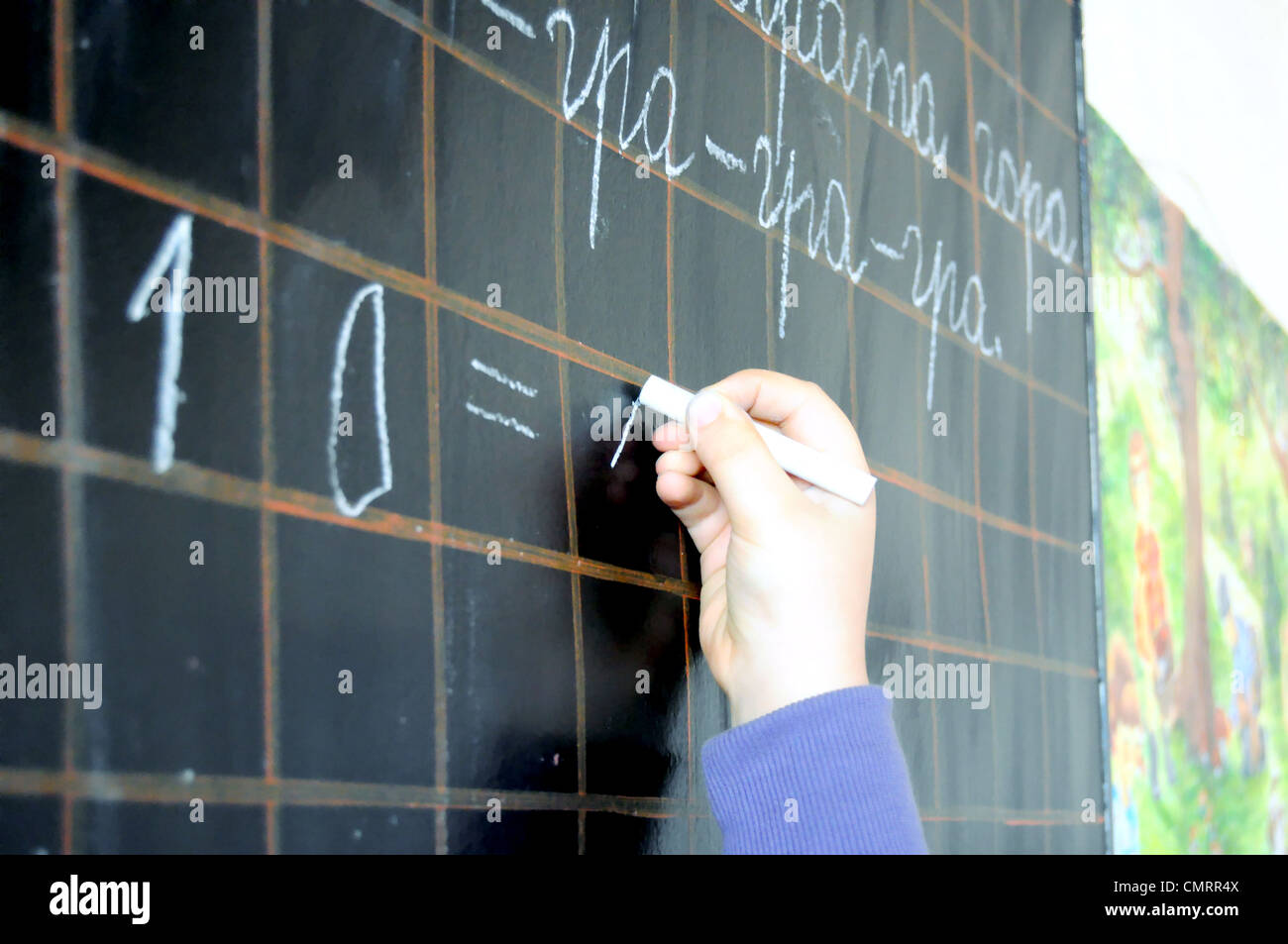 child hand writing numbers on school blackboard close up Stock Photo