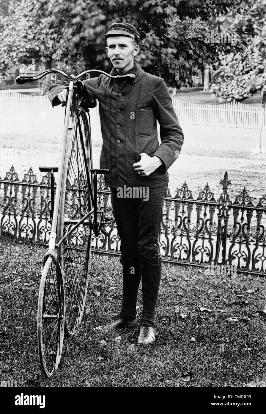 1880s 1890s MAN CALLED WHEELMAN WEARING CLOTHING FOR BICYCLE RIDING STANDING NEXT TO HIGH WHEEL RATCHET DRIVE BICYCLE Stock Photo