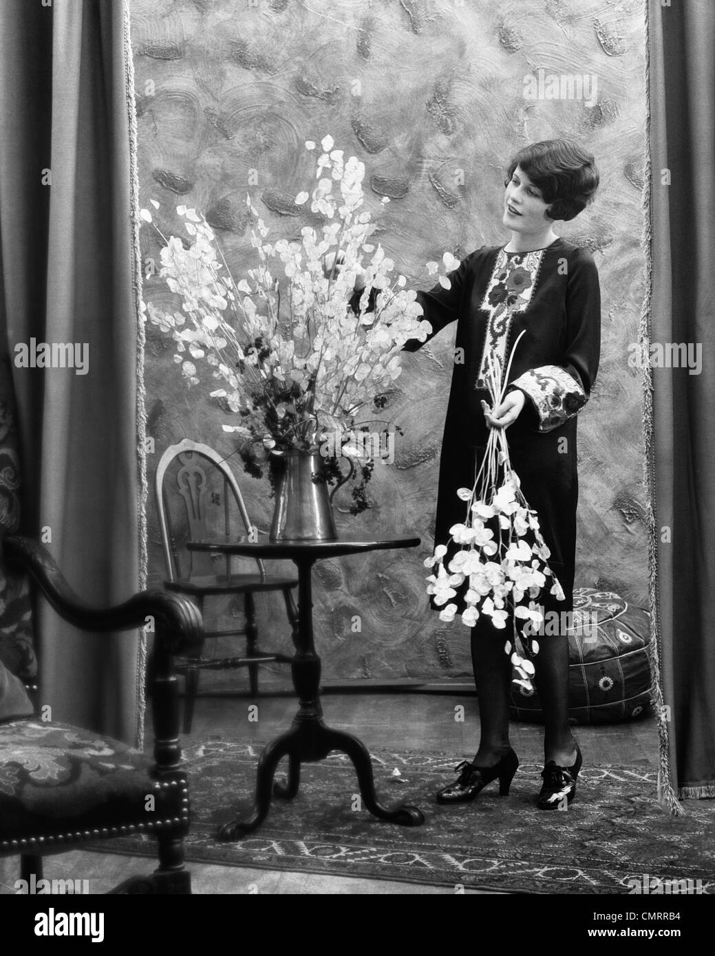 1920s WOMAN ARRANGING FLOWERS IN ALUMINUM PITCHER Stock Photo - Alamy, image size:1039x1390