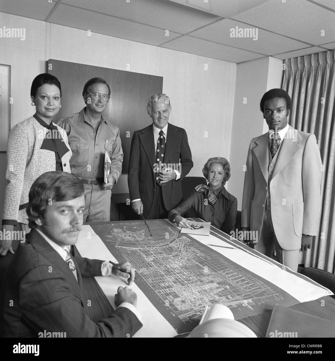 1970s PORTRAIT 6 BUSINESS PEOPLE MEN & WOMEN AROUND TABLE WITH BLUEPRINTS Stock Photo