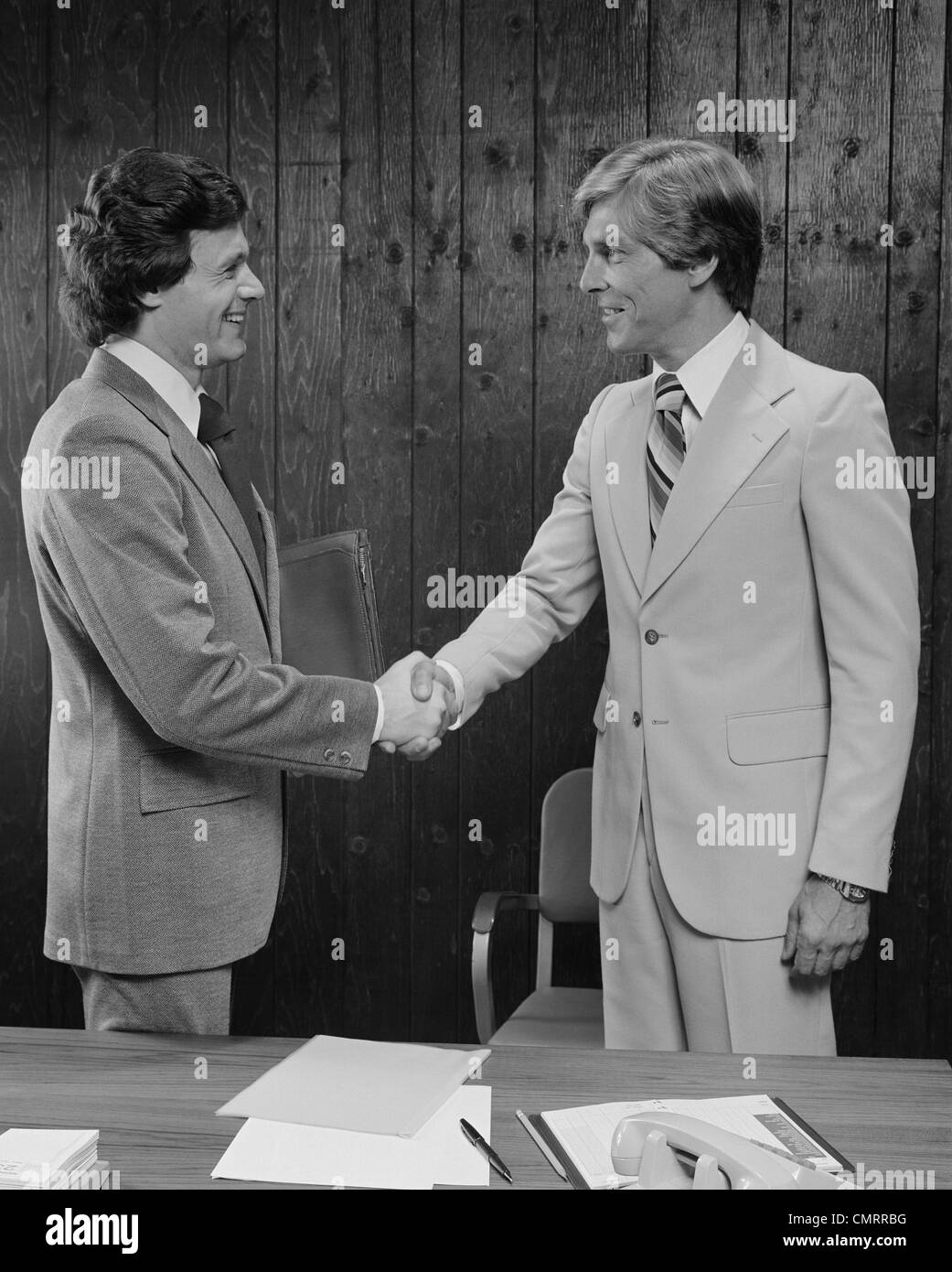 1970s 1980s TWO BUSINESSMEN SHAKING HANDS HANDSHAKE Stock Photo