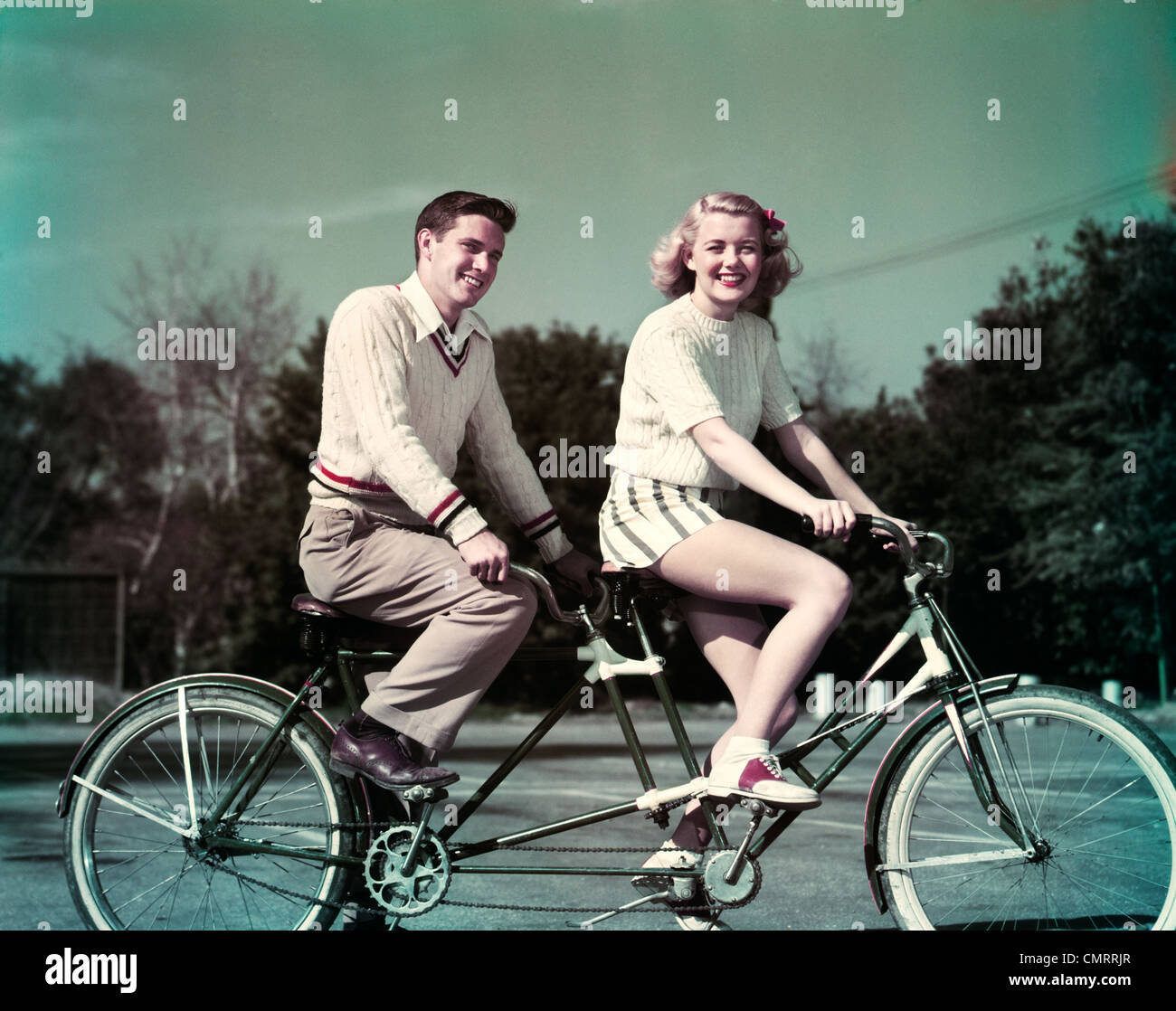 1950s SMILING  COUPLE RIDING TANDEM BICYCLE BUILT FOR TWO Stock Photo