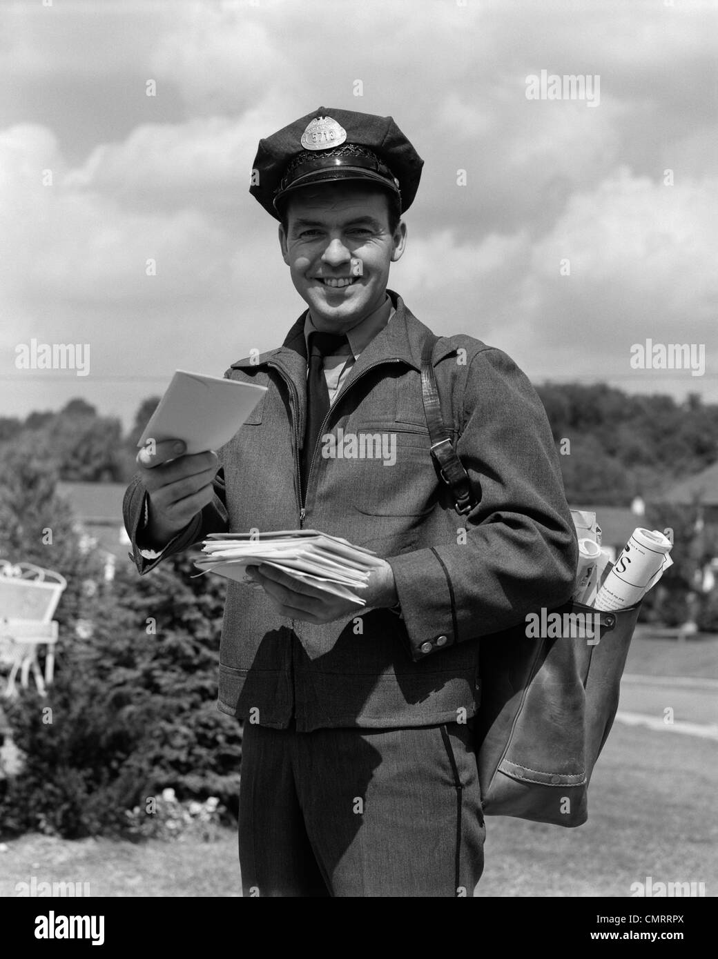 1950s MAN SMILING POSTMAN HOLDING OUT LETTER Stock Photo