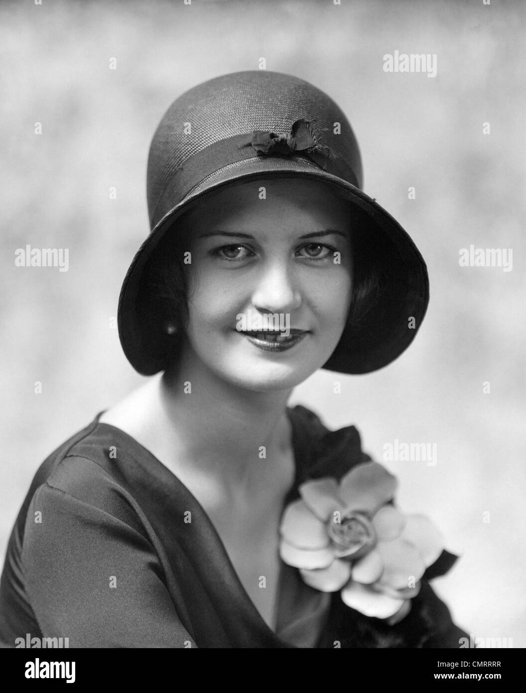 1930s HEAD & SHOULDERS PORTRAIT OF SMILING WOMAN WEARING HAT & FLOWER ON BLOUSE Stock Photo