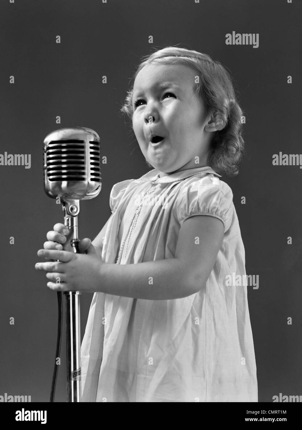 1940s LITTLE GIRL MAKING FACE SINGING INTO MICROPHONE Stock Photo