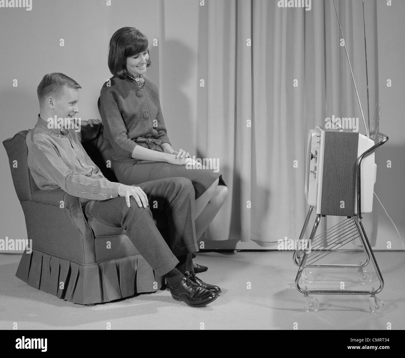 1960s COUPLE MAN WOMAN SITTING CHAIR WATCHING PORTABLE TELEVISION Stock ...