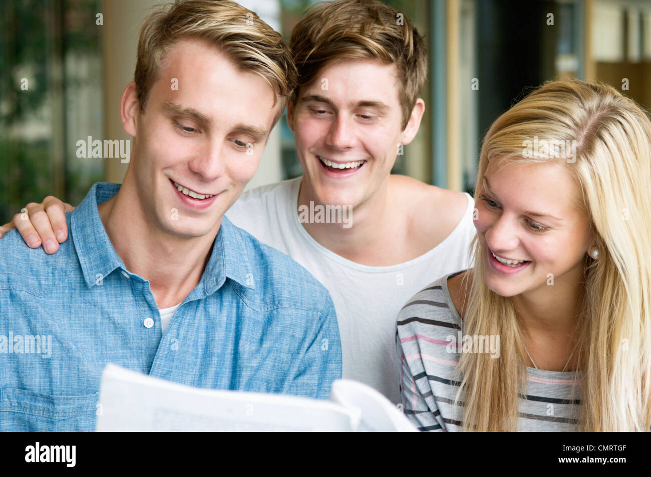 Three happy students reading booklet Stock Photo