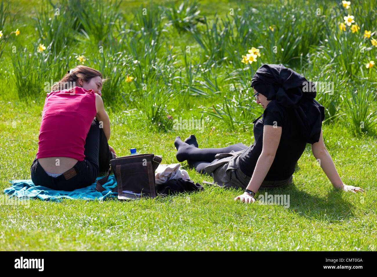Two women lazing on the grass amidst spring daffodils - Christ Church College Meadows during the Times Literary Festival 2012 Stock Photo