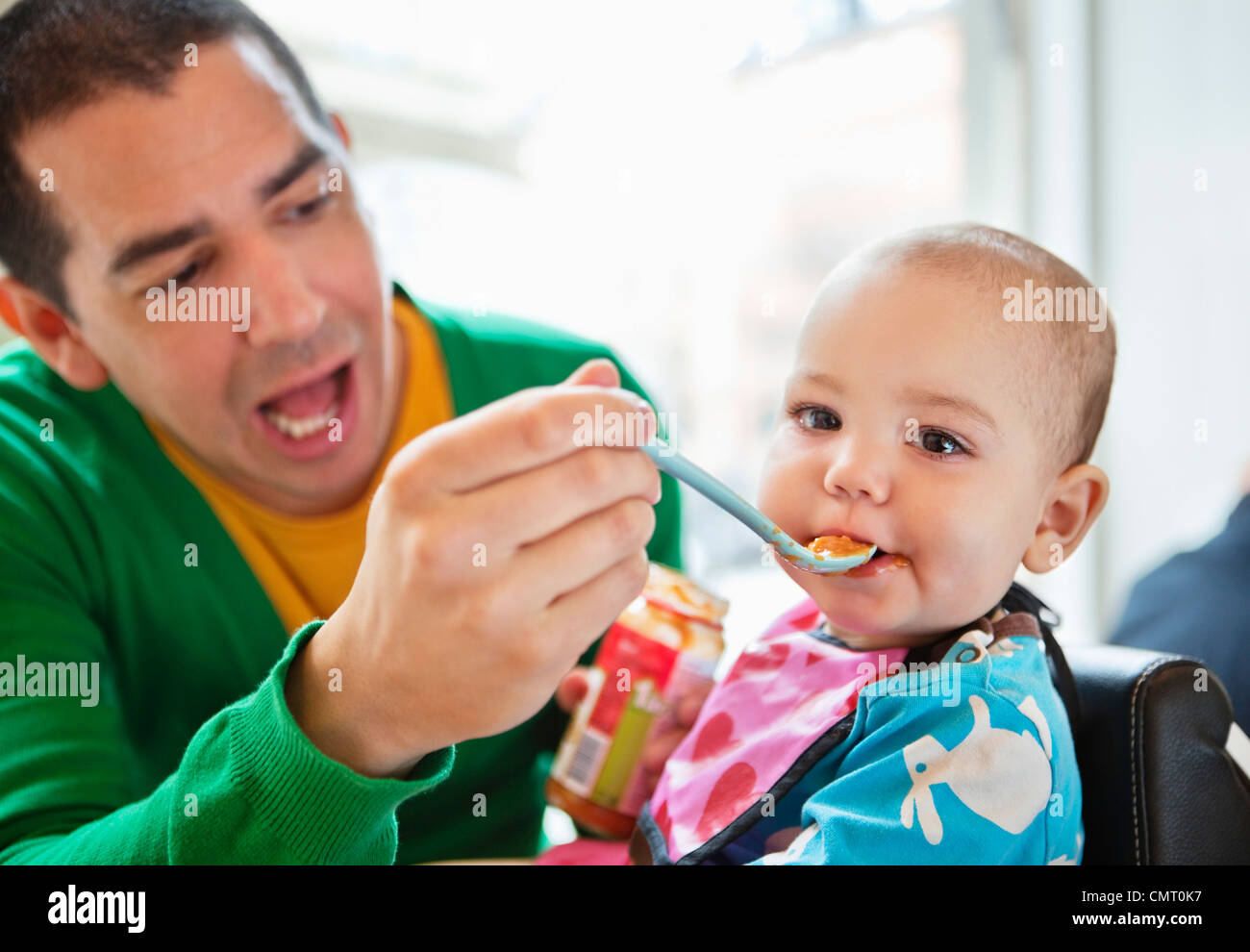 Father feeding baby with plastic spoon Stock Photo