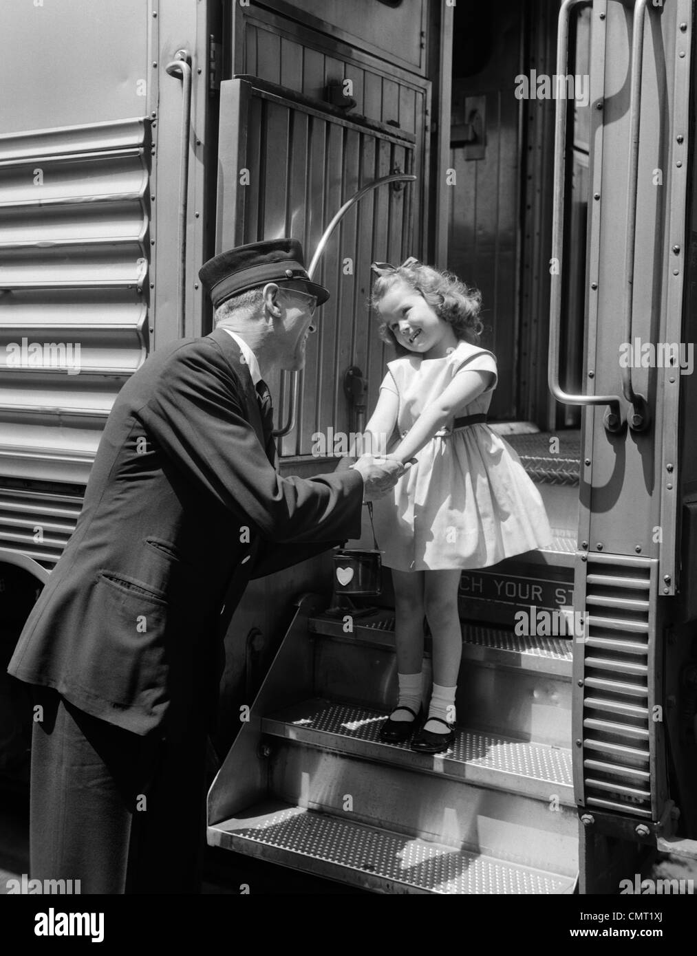 1950s CONDUCTOR GREETING LITTLE GIRL ON TRAIN STEPS Stock Photo