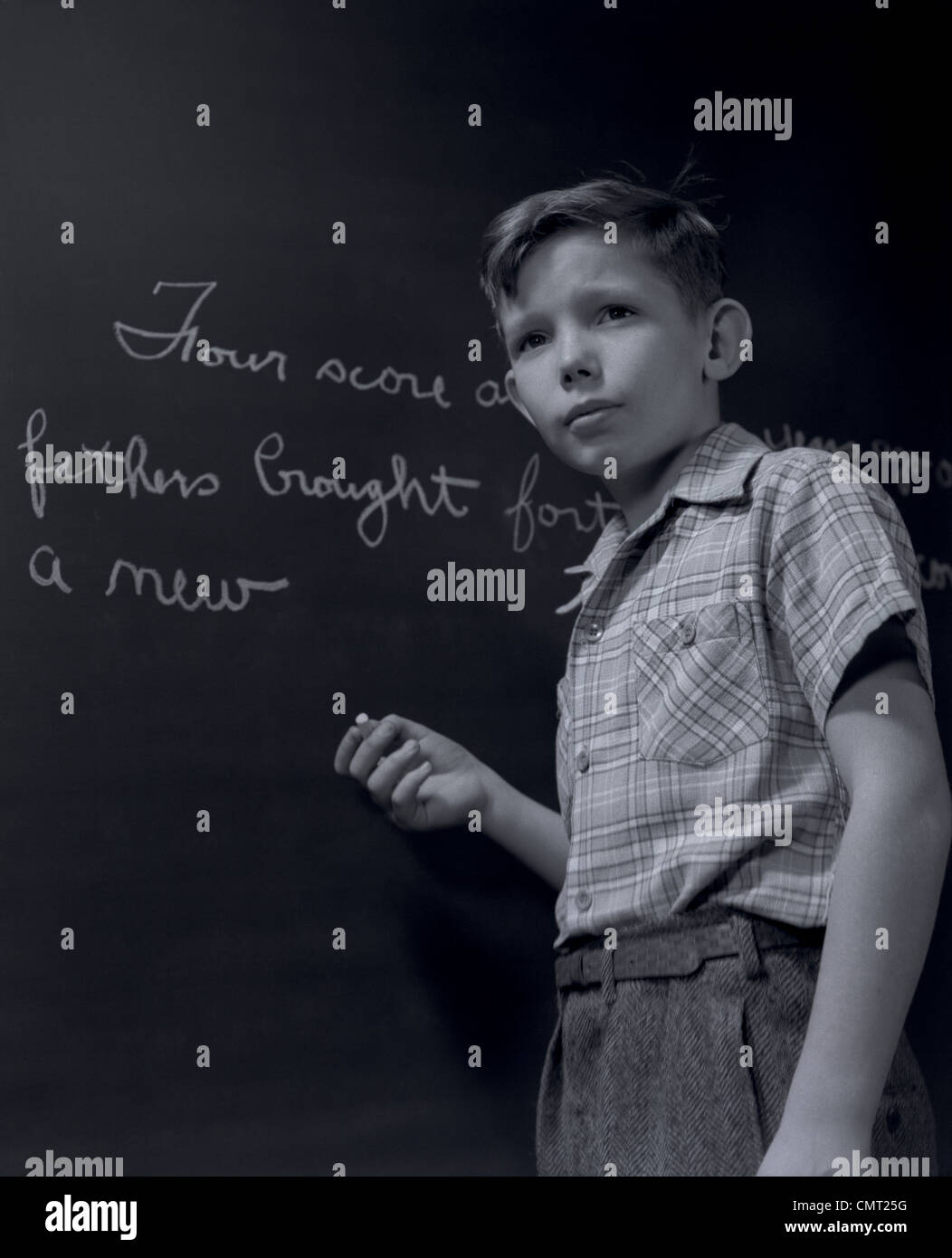 1940s GRADE SCHOOL BOY AT CHALKBOARD WRITING OUT GETTYSBURG ADDRESS Stock Photo