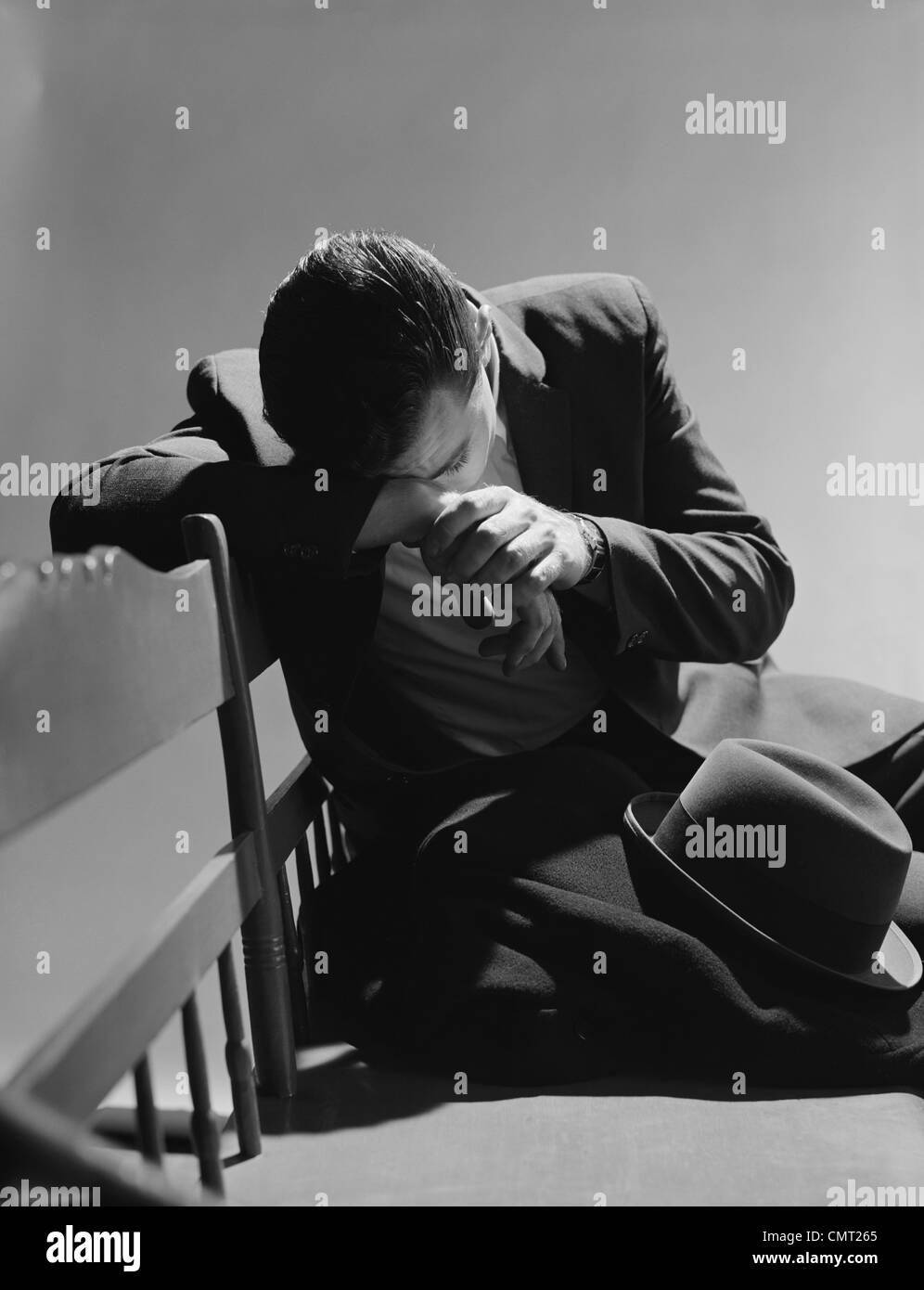 1960s BUSINESSMAN SITTING ON BENCH HEAD DOWN ON ARMS SLUMPED OVER SAD DEPRESSED Stock Photo