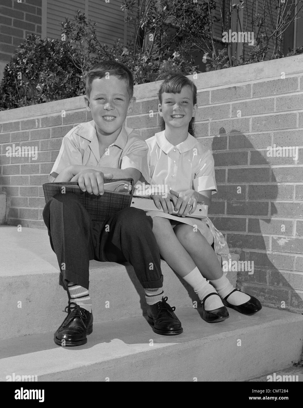 1960s BOY GIRL SITTING STEPS HOLDING SCHOOL BOOKS Stock Photo