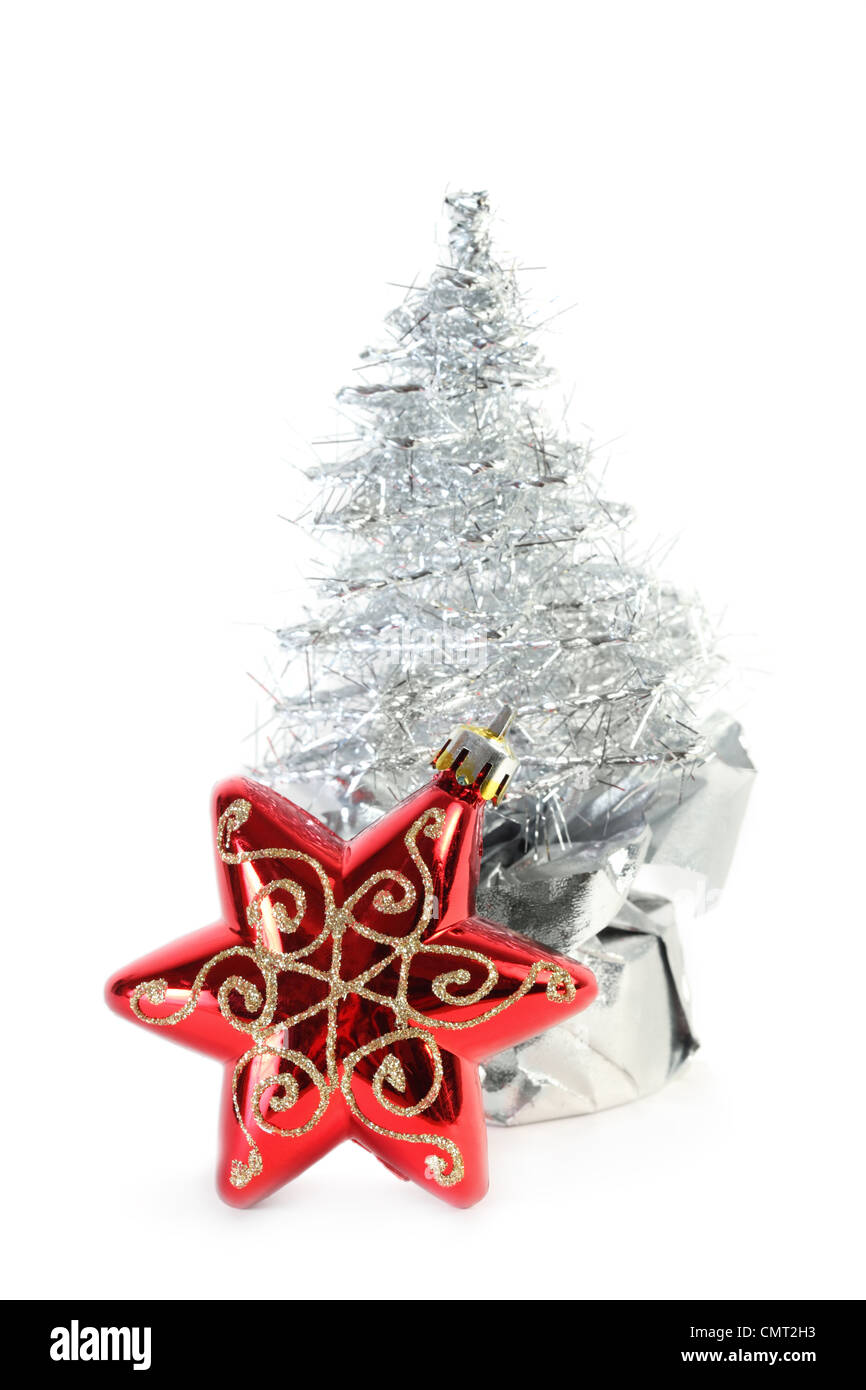 Red Christmas tree star and silver artificial Christmas tree made of tinsel grows from gift wrapping, star in focus Stock Photo