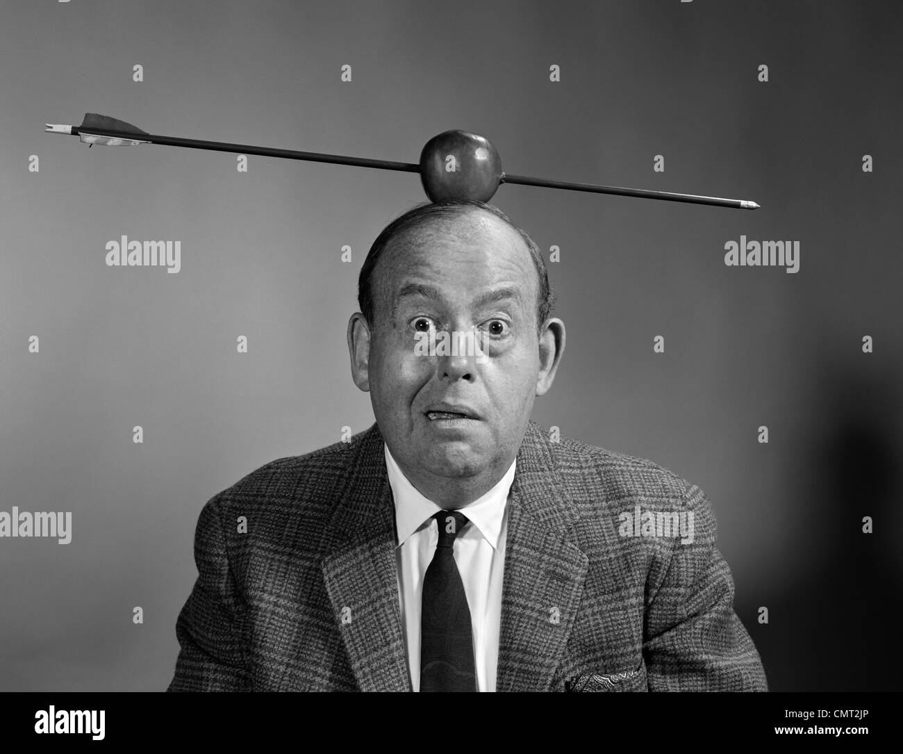 1960s PORTRAIT MAN WITH ARROW THROUGH APPLE ON HEAD LOOKING AT CAMERA
