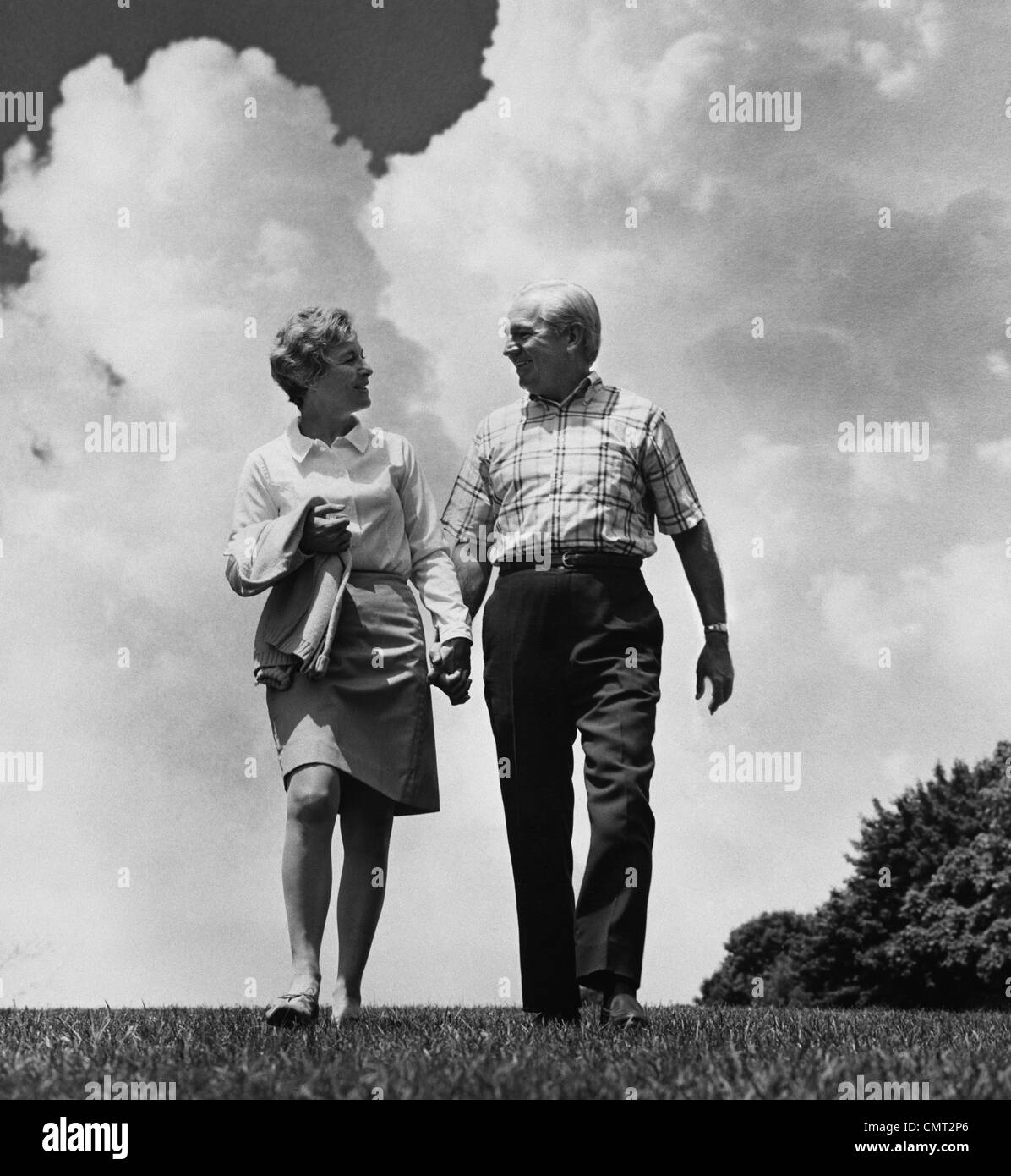 1960s MATURE COUPLE WALKING TALKING HOLDING HANDS Stock Photo