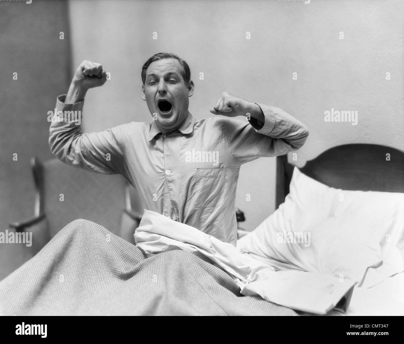 1930s MAN IN BED WAKING UP YAWNING AND STRETCHING Stock Photo