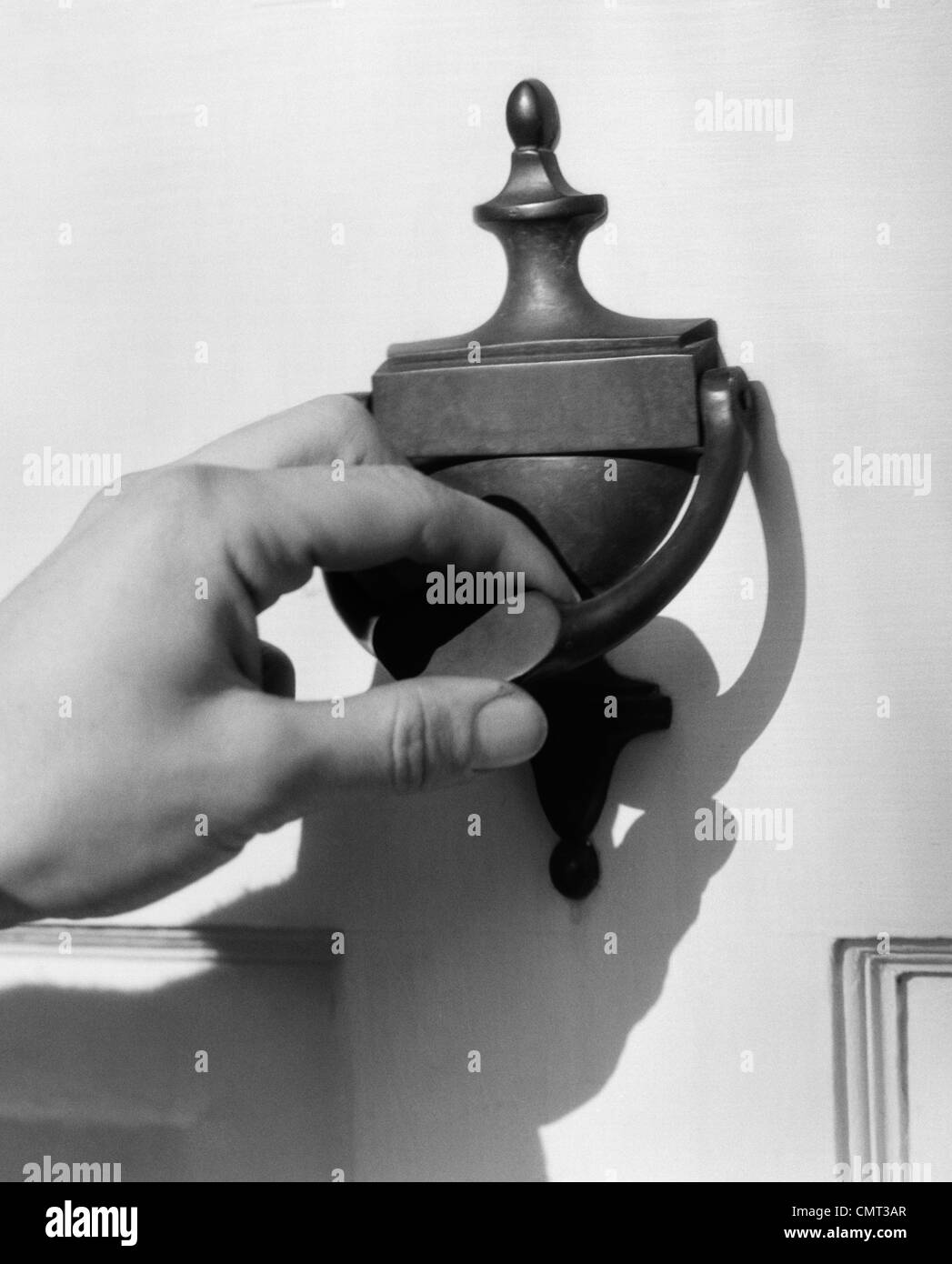1930s MAN'S HAND LIFTING DOOR KNOCKER Stock Photo