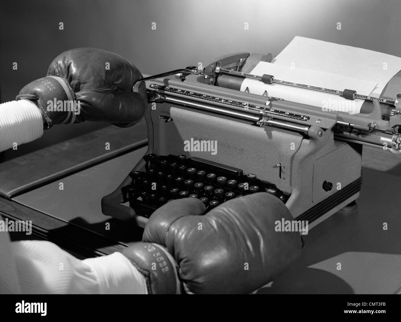 1950s SYMBOLIC HANDS WEARING BOXING GLOVES RETURNING CARRIAGE ON OFFICE TYPEWRITER Stock Photo