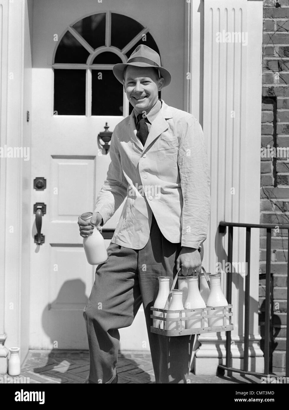 1940s MILKMAN SMILING AT CAMERA ON DOORSTEP DELIVERING MILK Stock Photo