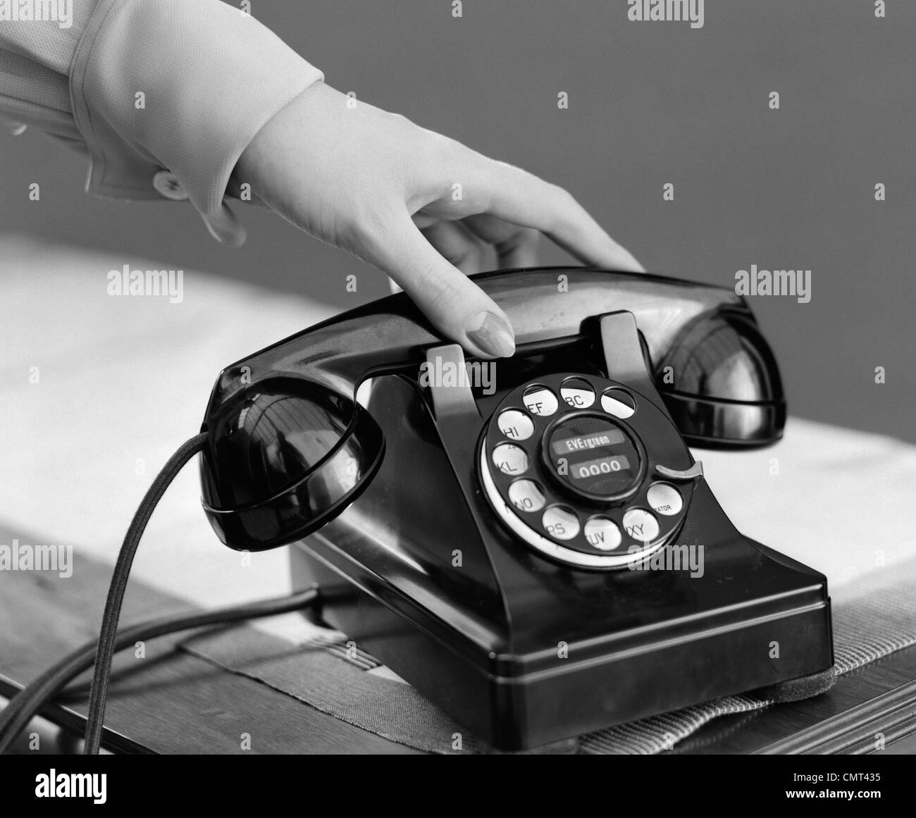 1940s WOMAN'S HAND PICKING UP PHONE RECEIVER Stock Photo