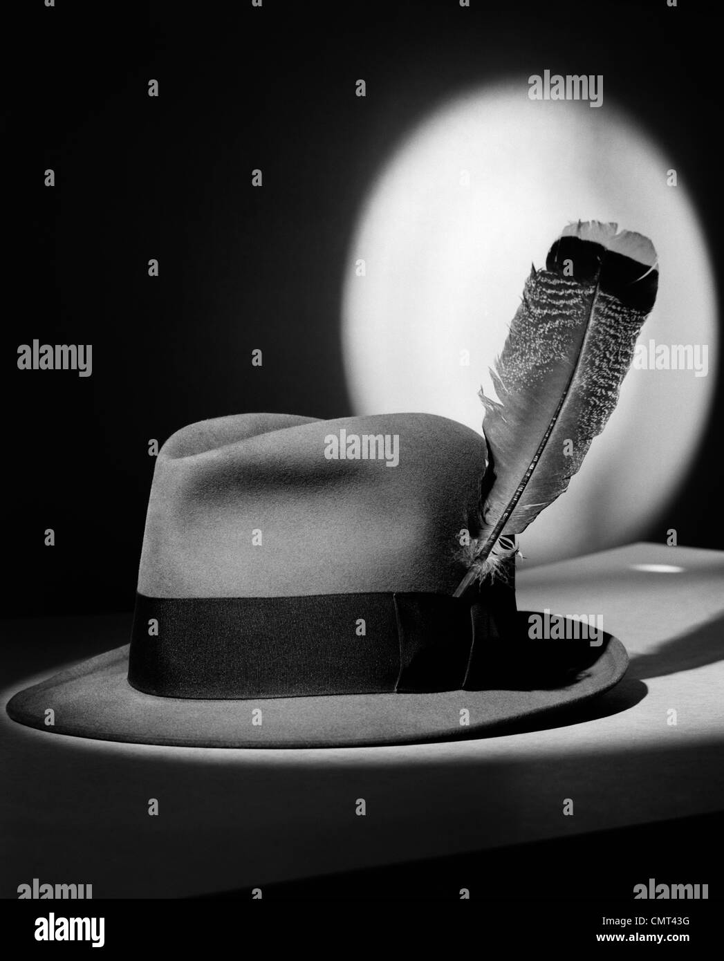1940s FEDORA HAT WITH FEATHER IN BAND IN SPOTLIGHT SYMBOLIC FEATHER IN YOUR CAP Stock Photo