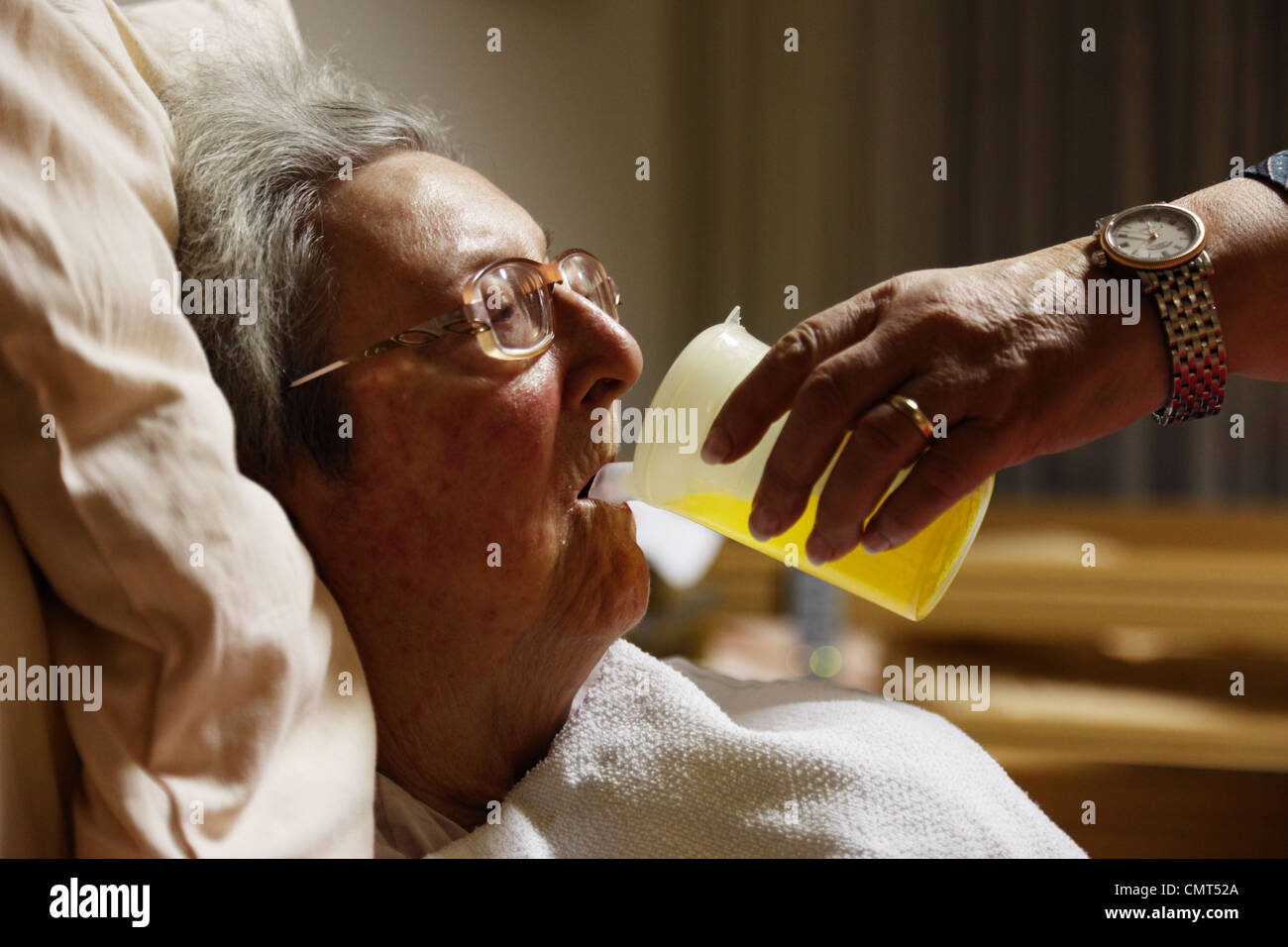 people, old age, retirement home, Altenzentrum der St. Clemens Hospitale in Sterkrade, older woman lies in a sickbed, aged 70 to 85 years, physical handicap, dementia illness, nurse holds a feeding cup and helps her to drink, Waltraut, Elke, D-Oberhausen, Stock Photo
