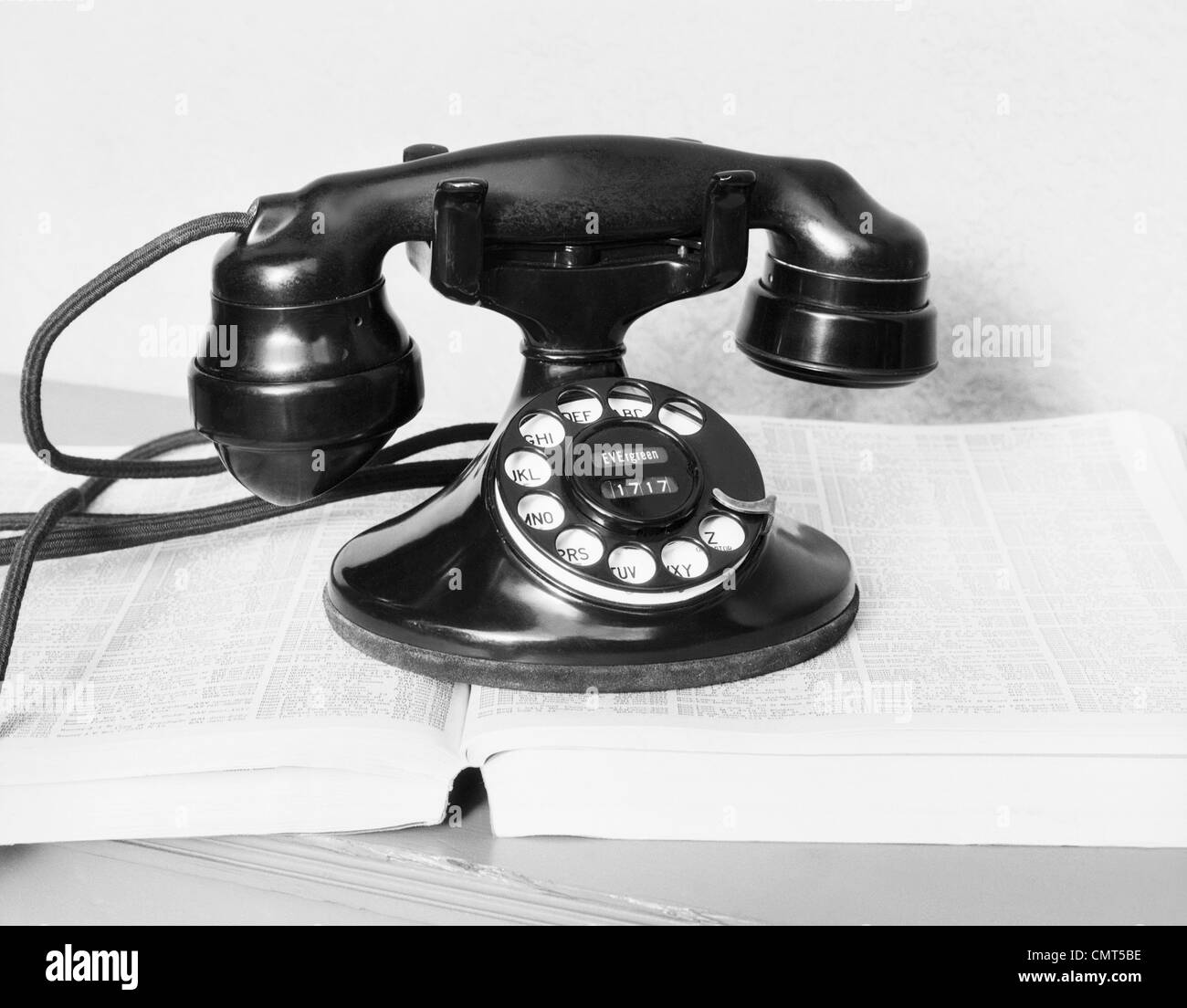 1930s OLD BLACK ROTARY DIAL CRADLE TELEPHONE ON OPEN TELEPHONE NUMBER DIRECTORY BOOK Stock Photo