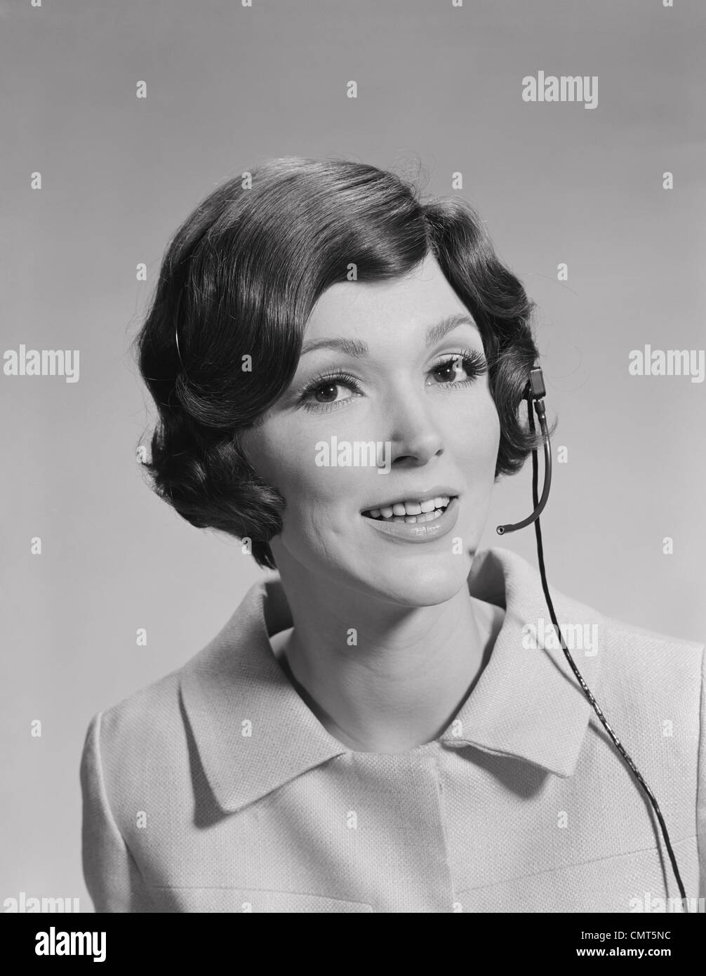 1970s SMILING BRUNETTE WOMAN WEARING TELEPHONE HEAD SET Stock Photo