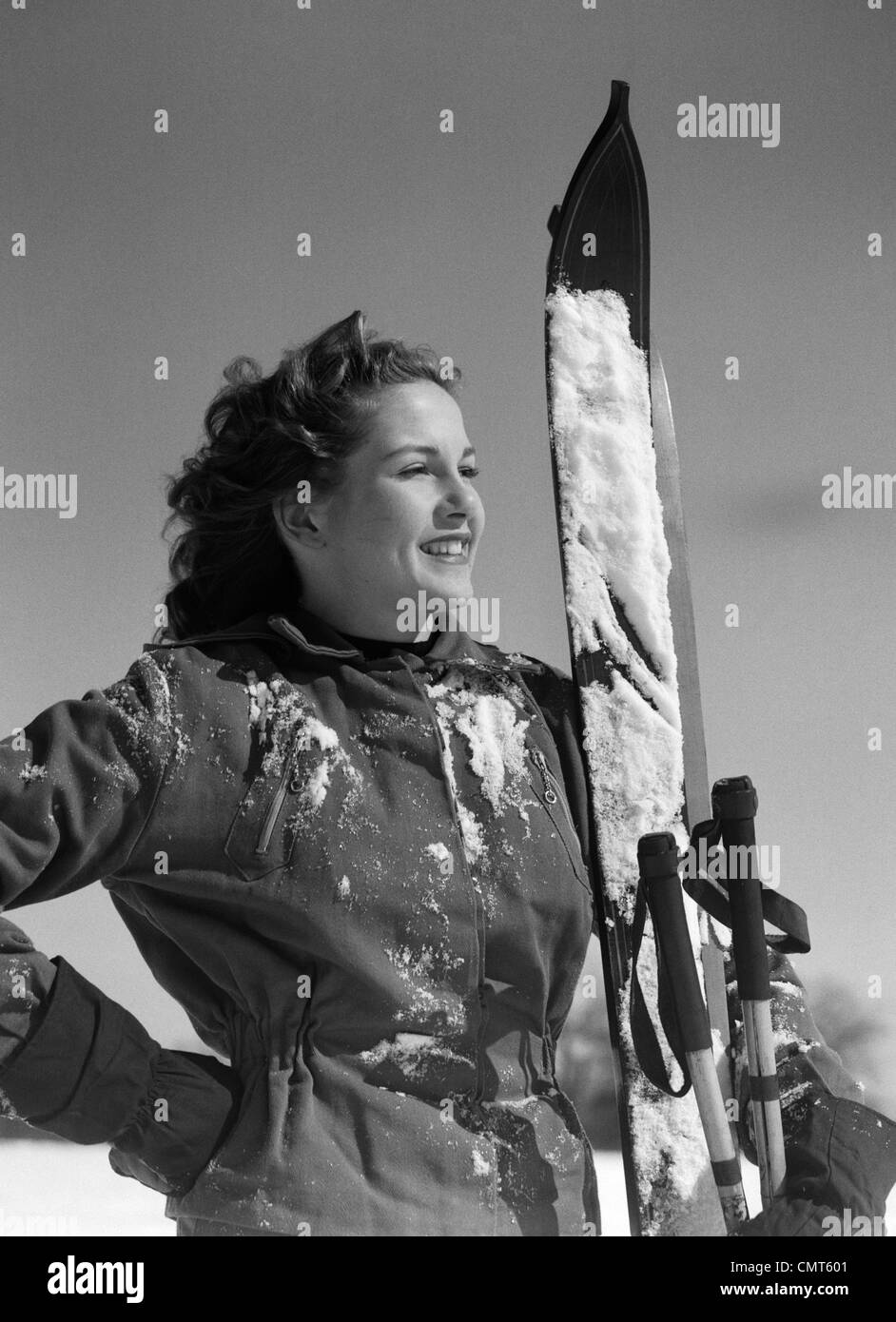 1940s SMILING WOMAN PORTRAIT HOLDING SKIS AND SKI POLES WINTER OUTDOOR Stock Photo