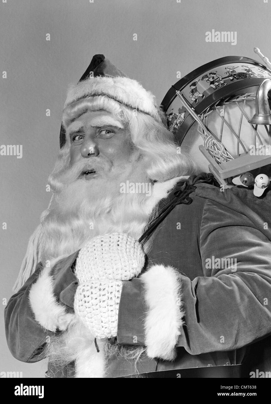 1940s PORTRAIT OF SMILING SANTA CLAUS WITH A SACK FOR OF TOY PRESENTS SLUNG OVER HIS SHOULDER LOOKING AT CAMERA Stock Photo