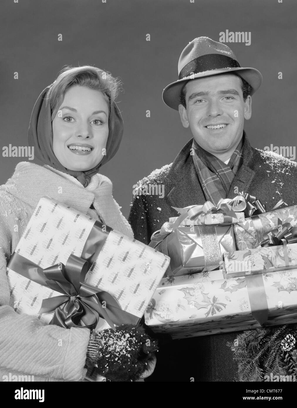 1960s COUPLE MAN AND WOMAN HOLDING WRAPPED CHRISTMAS PRESENTS AND PACKAGES Stock Photo