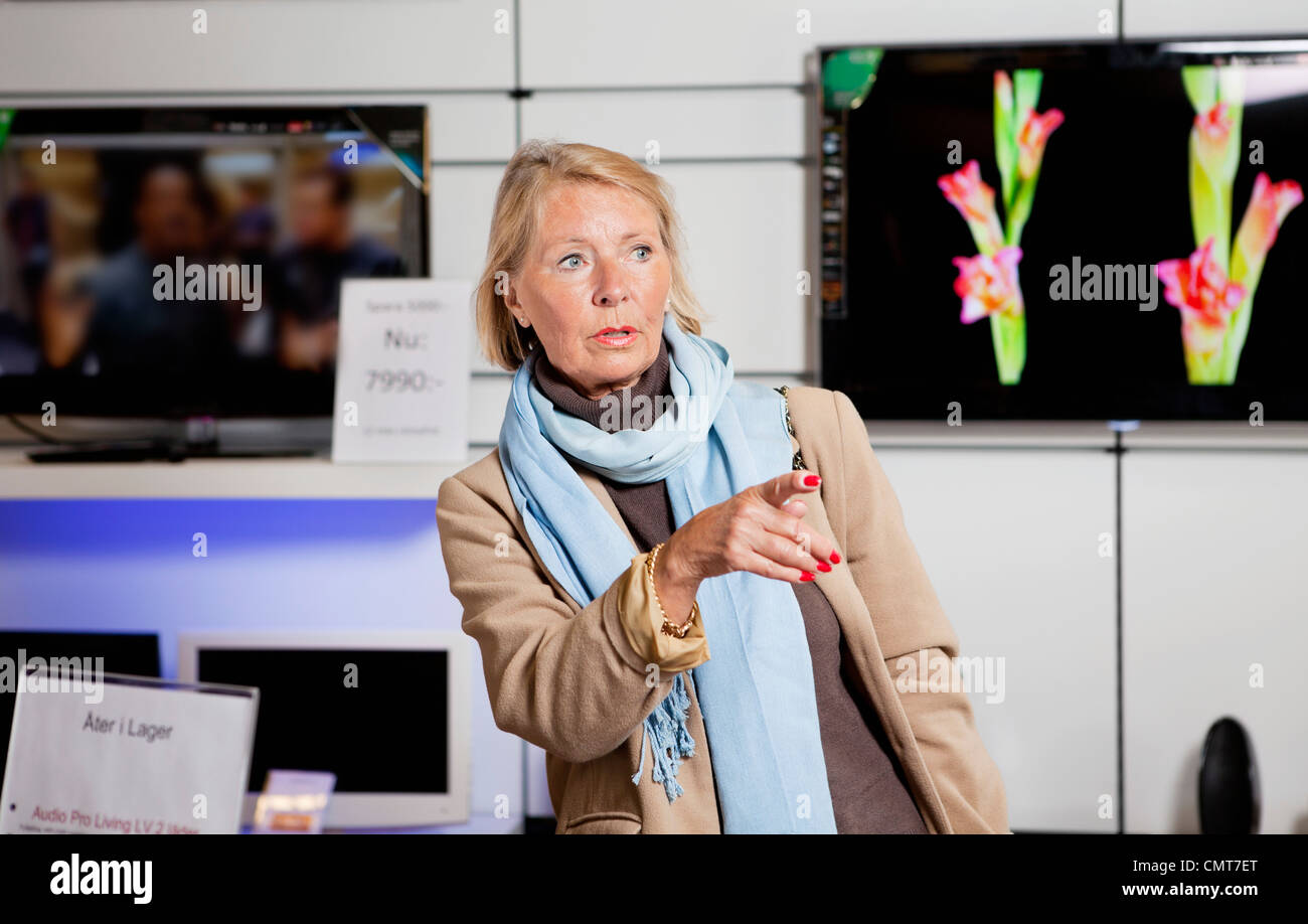 Senior woman in TV shop gesturing Stock Photo