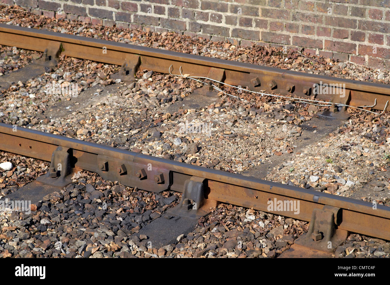 Old railway track - bullhead rail in iron chairs with rails joined by bolted fishplates. Note track circuit wires. Stock Photo