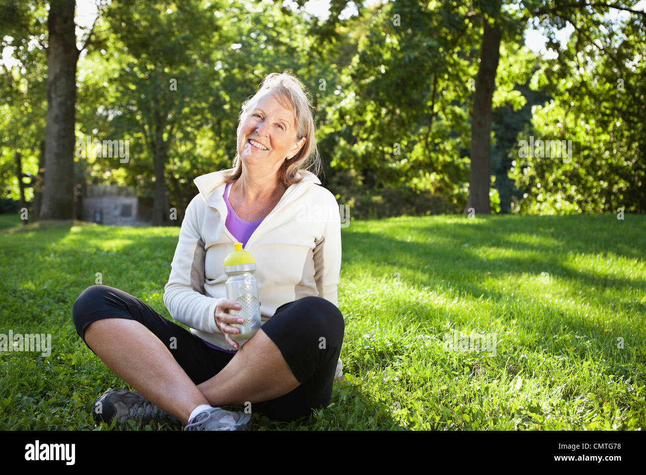 Portrait of smiling woman sitting on grass in park Stock Photo - Alamy