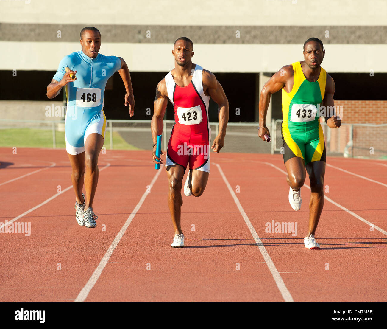 Runners running on track in relay race Stock Photo