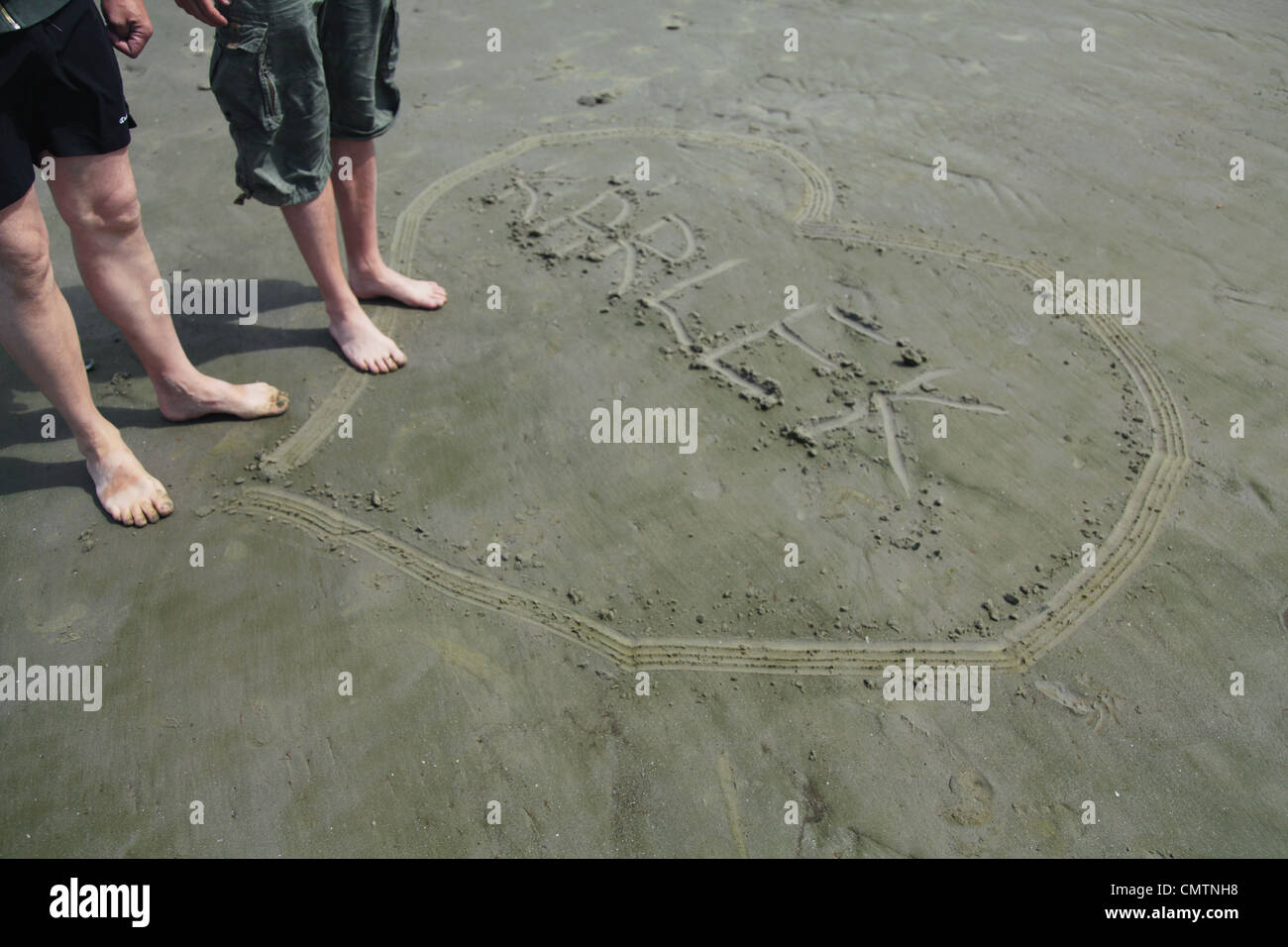 High angle view of human legs and heart on beach Stock Photo