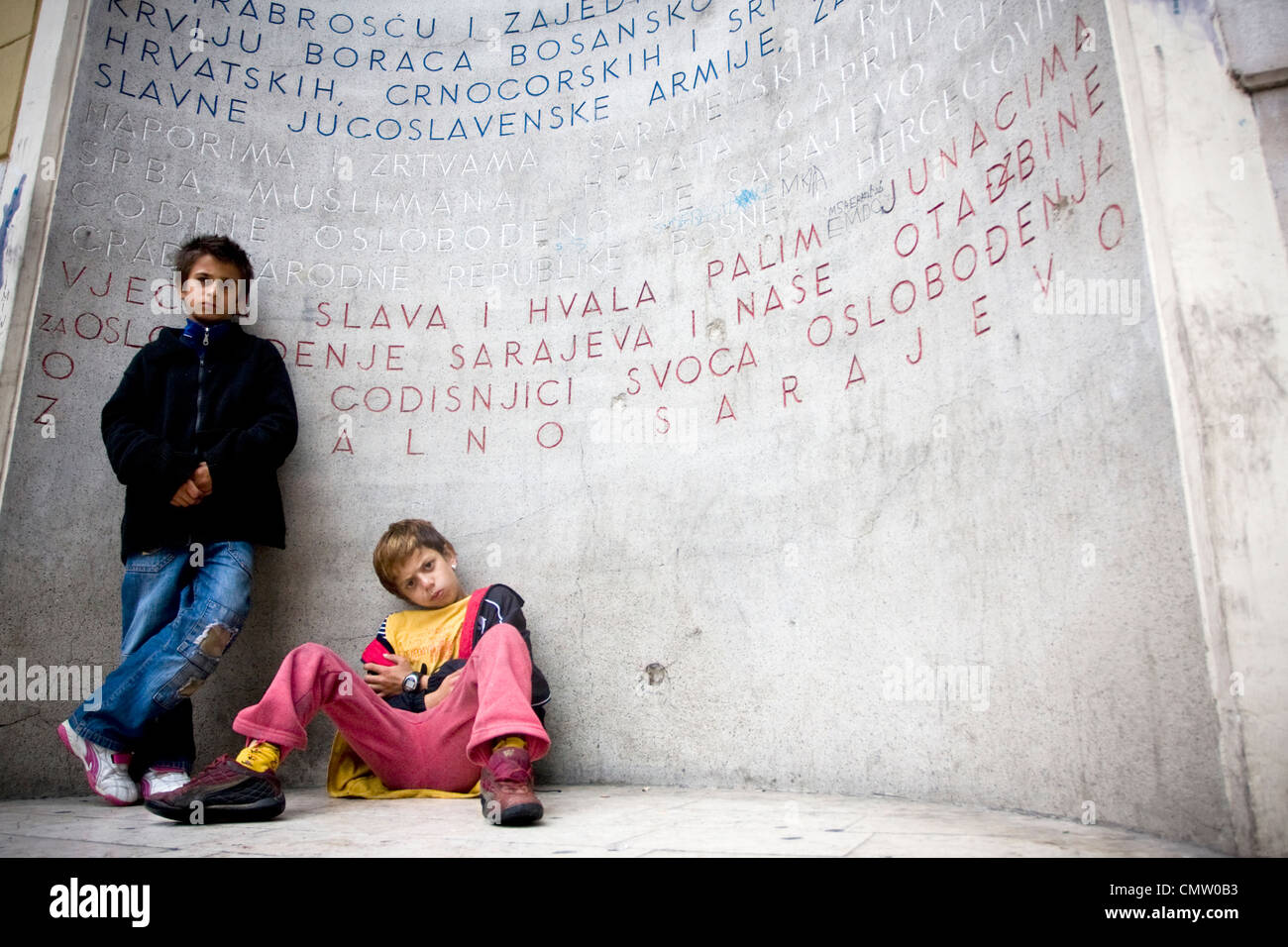 A Roma boys in front of monument of victims of WWII monument (Eternal Flame) in center of Bosnian capital of Sarajevo. Stock Photo