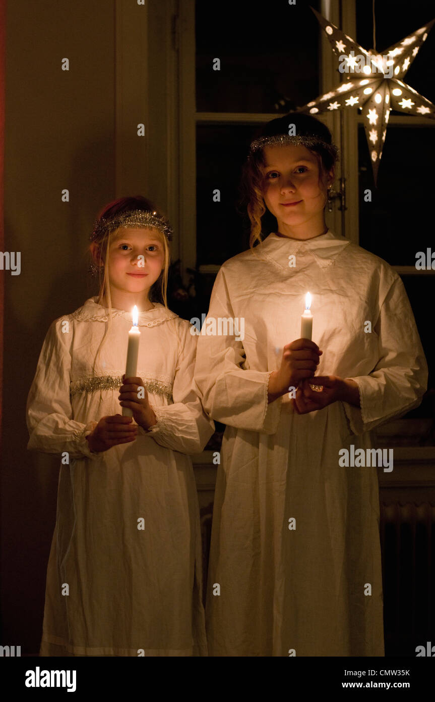 Girls traditionally dressed standing with candles on St. Lucia's Day Stock Photo
