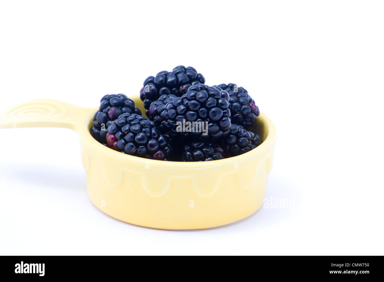 Fresh blackberries in a yellow bowl on white background Stock Photo
