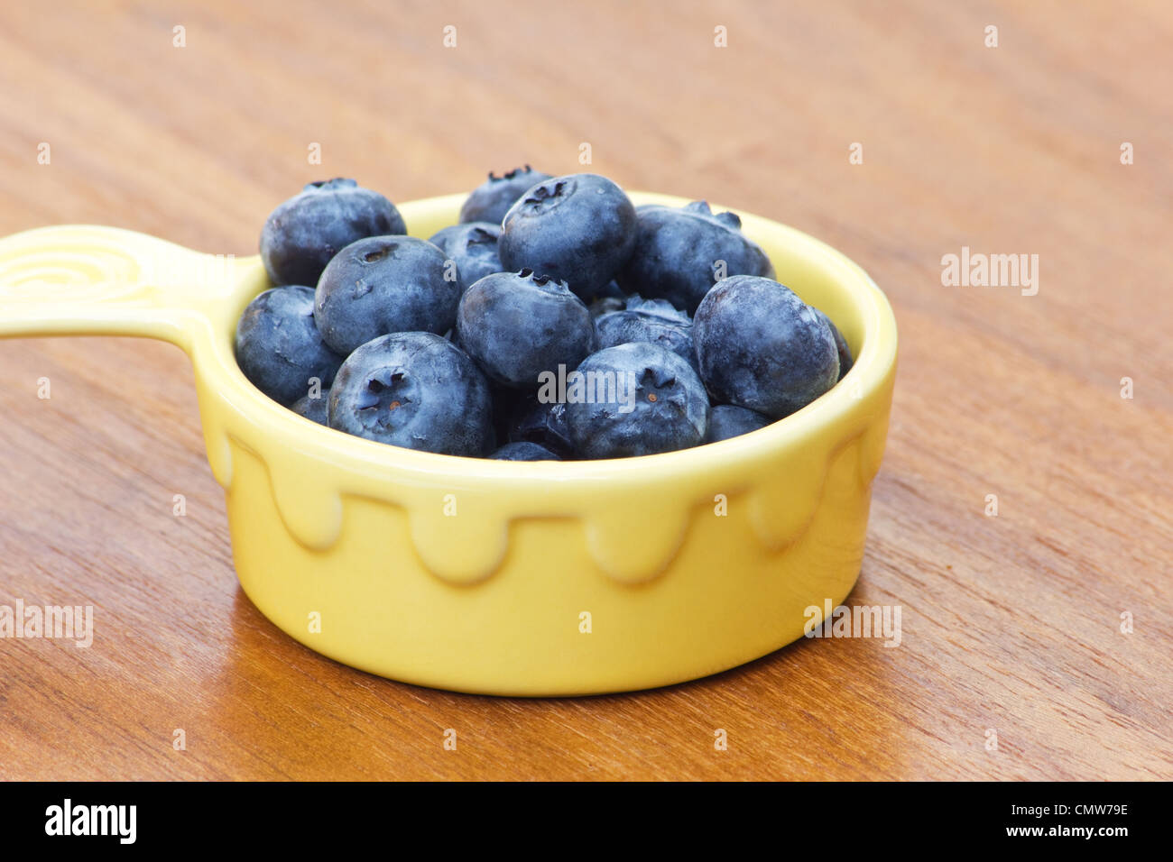 Blueberries in a yellow bowl on wooden background Stock Photo