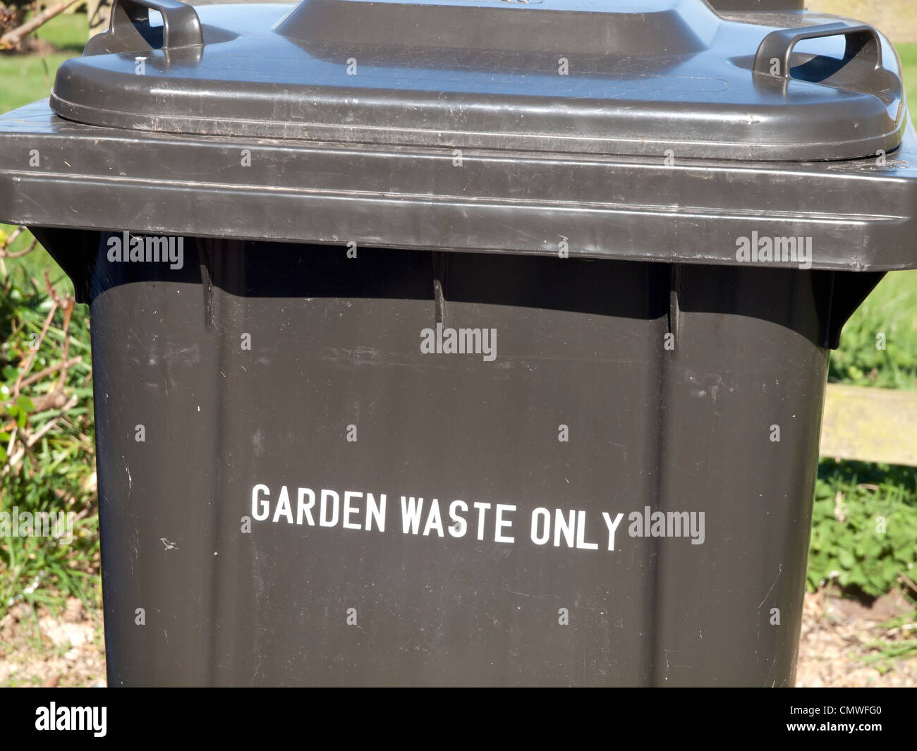 A grey recycling wheelie bin labeled Garden Waste Only Stock Photo